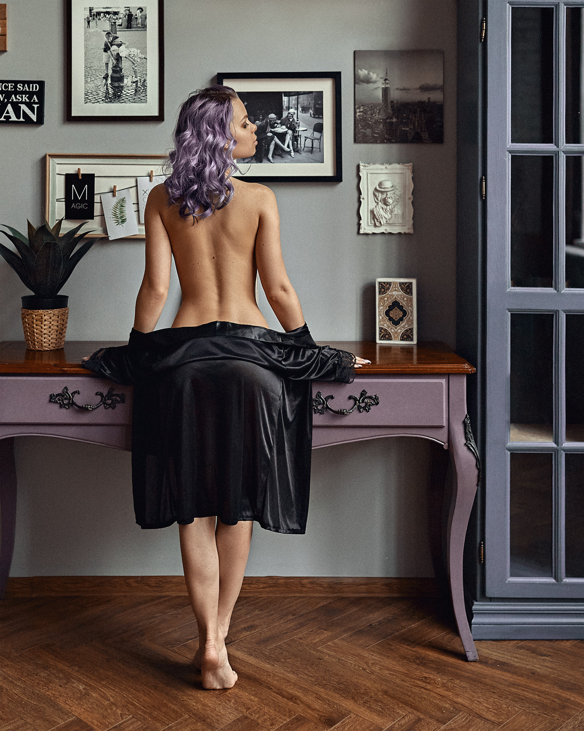 Красивая девушка стоит около столика в комнате.