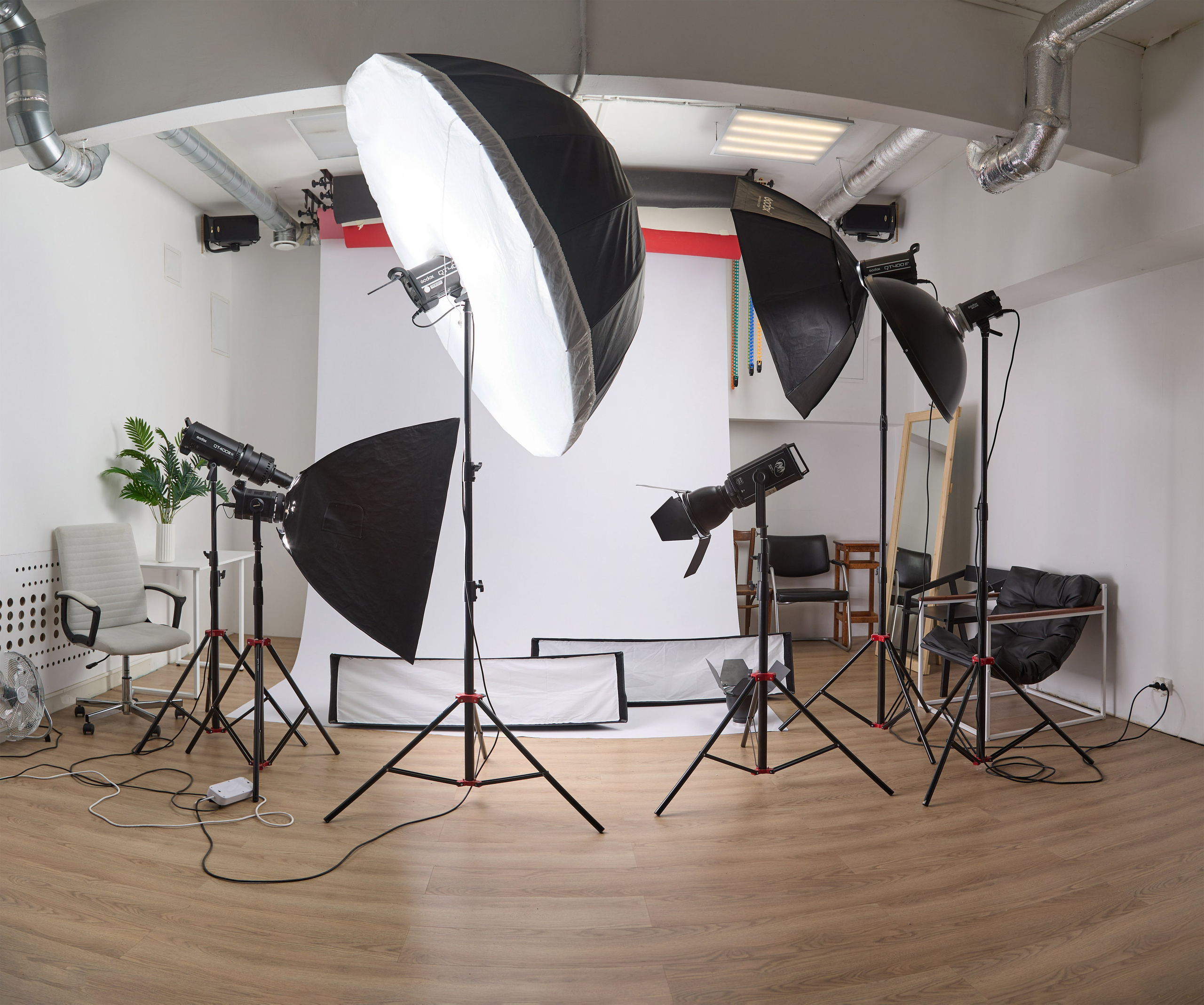 Фото профессиональной фотостудии с осветительным оборудованием и фонами для съемок.