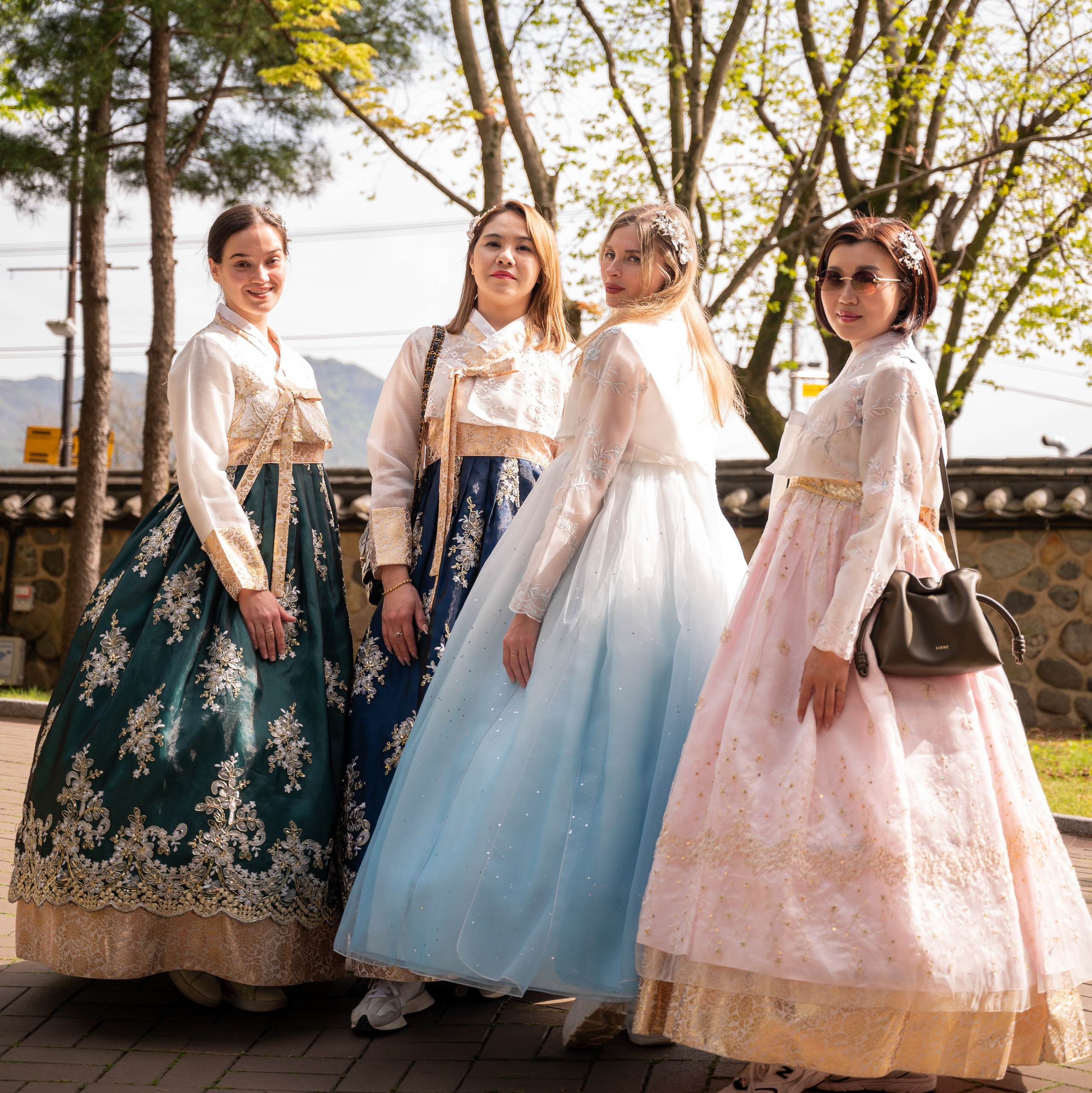 Three friends in hanbok by a traditional fence in autumn — hanbok photoshoot in Busan · 부산 한복 스냅