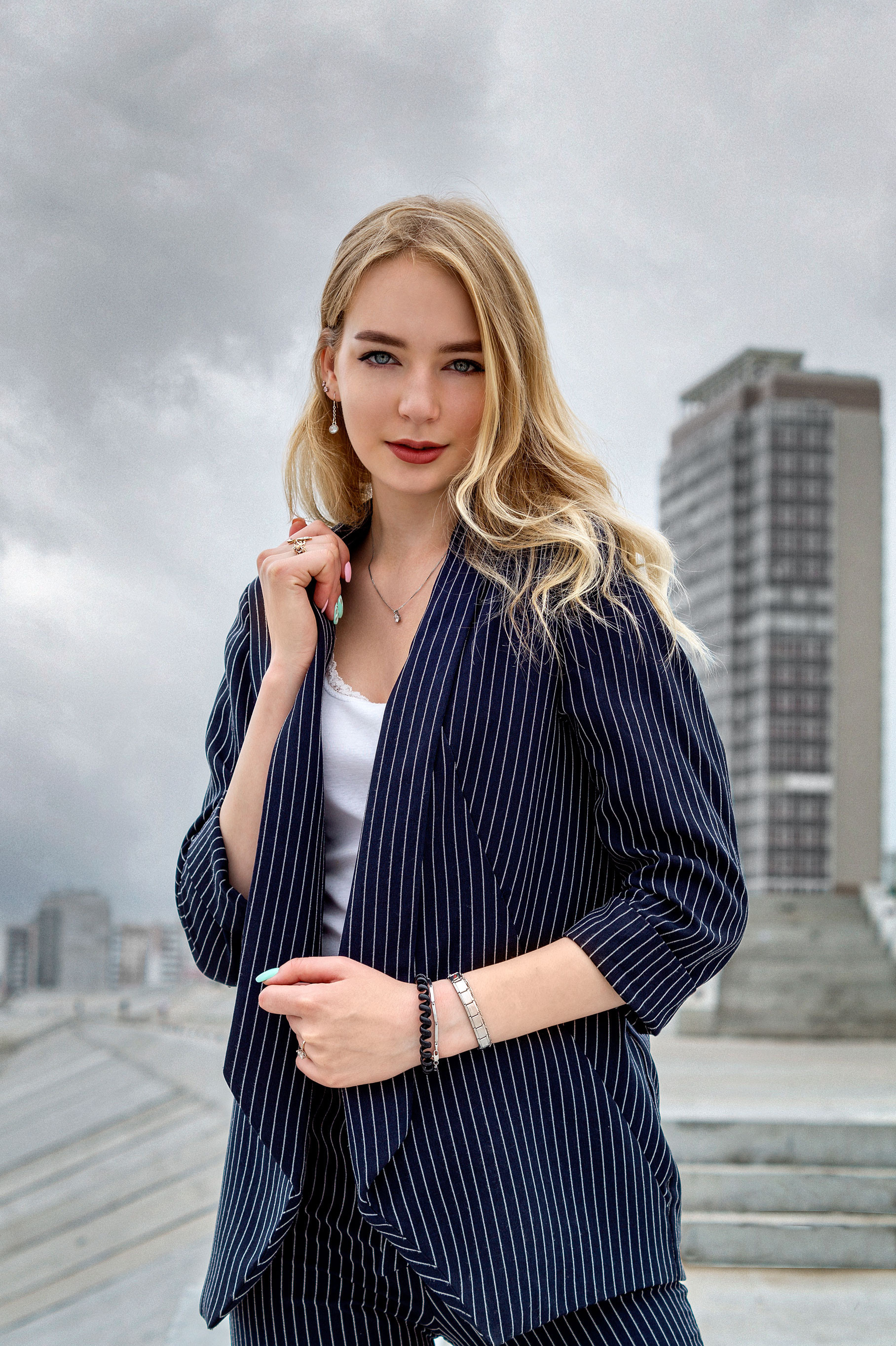 Портрет девушки в синем пальто на фоне кирпичной стены.