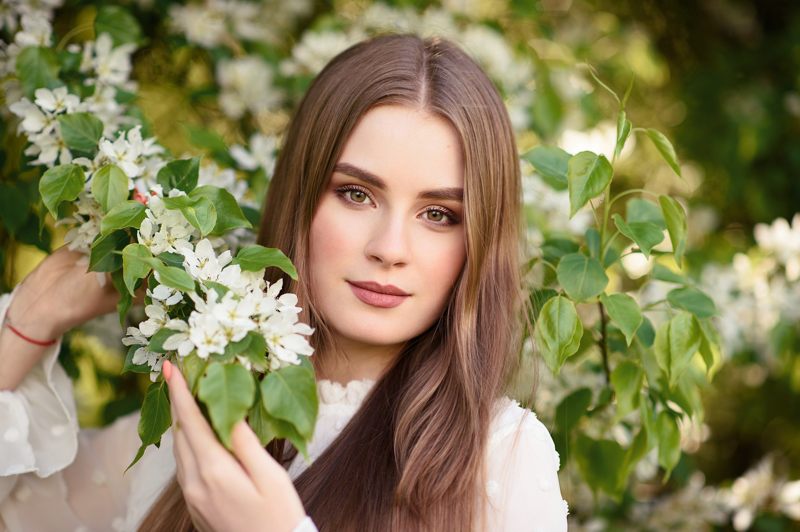 Красивая молодая девушка в белом цветении яблонь