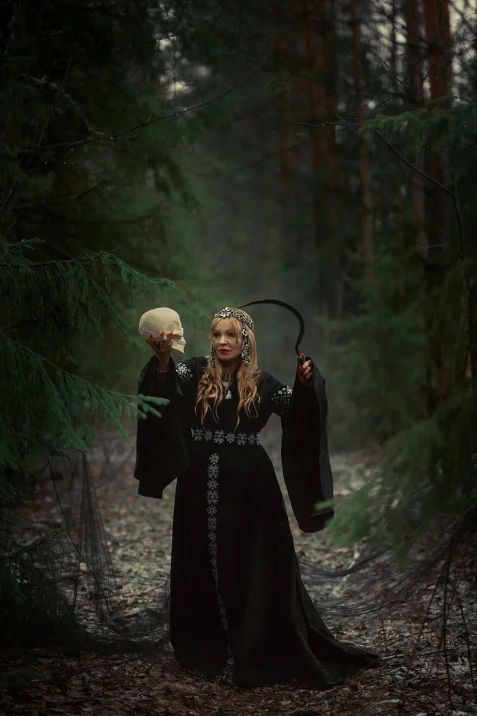 Отличный и выразительный образ Морены — богини смерти, зимы и перехода.  Женщина в чёрном славянском платье с черепом в руке, образ богини Морены. Славянская богиня смерти в лесу с косой и черепом, этно-фотосессия. Фотосессия в славянском стиле — Морена, богиня мрака и холода. Таинственная женщина в черном с черепом — образ славянской Морены. Девушка в лесу с косой и черепом в образе богини зимы. 