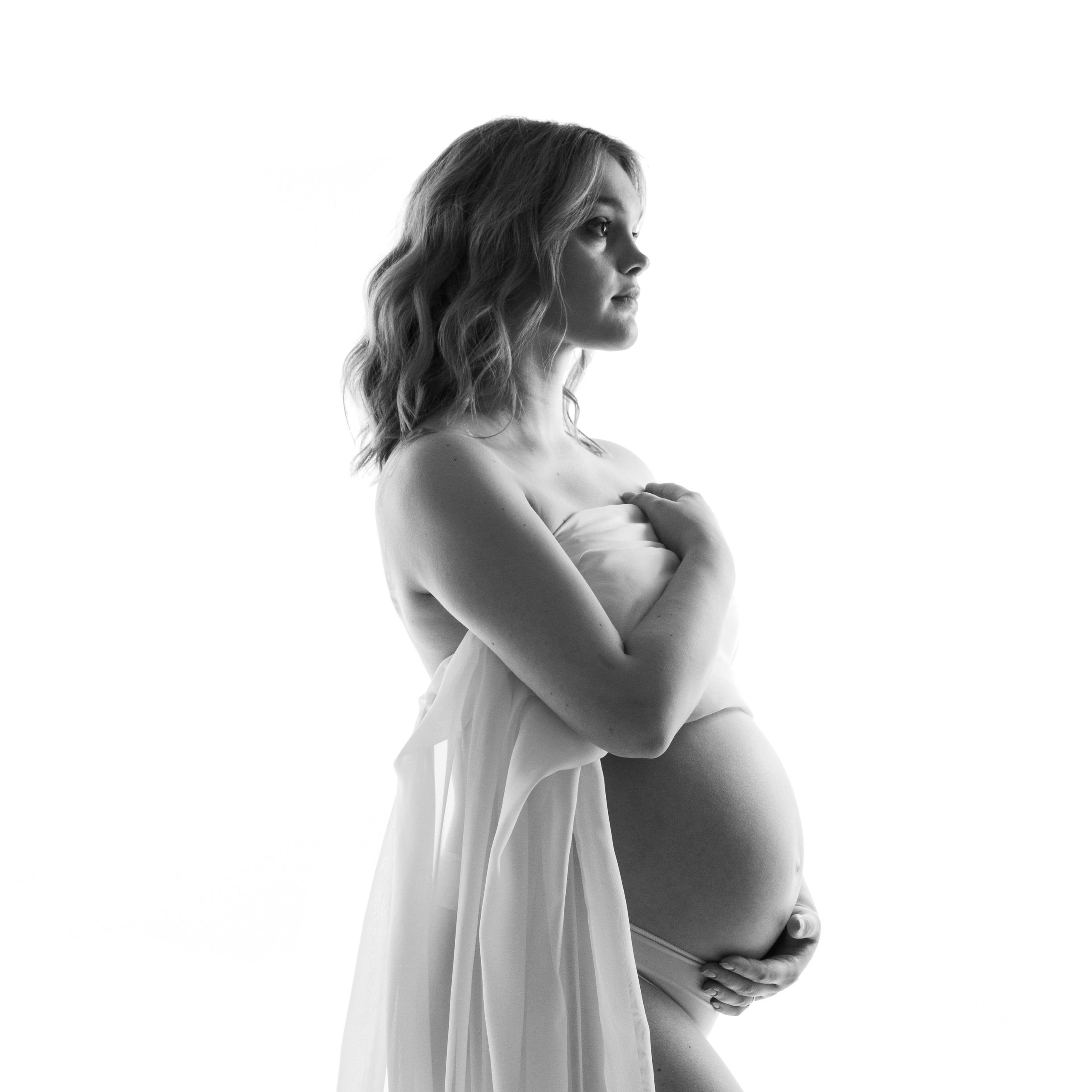 беременная девушка в белой полупрозрачной ткани 