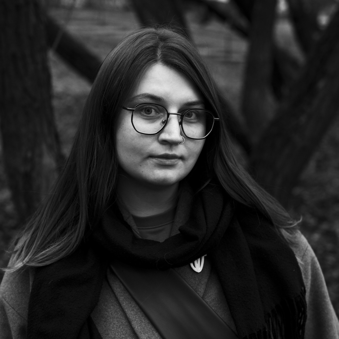 Черно-белый портрет девушки фотографа в очках и пальто 