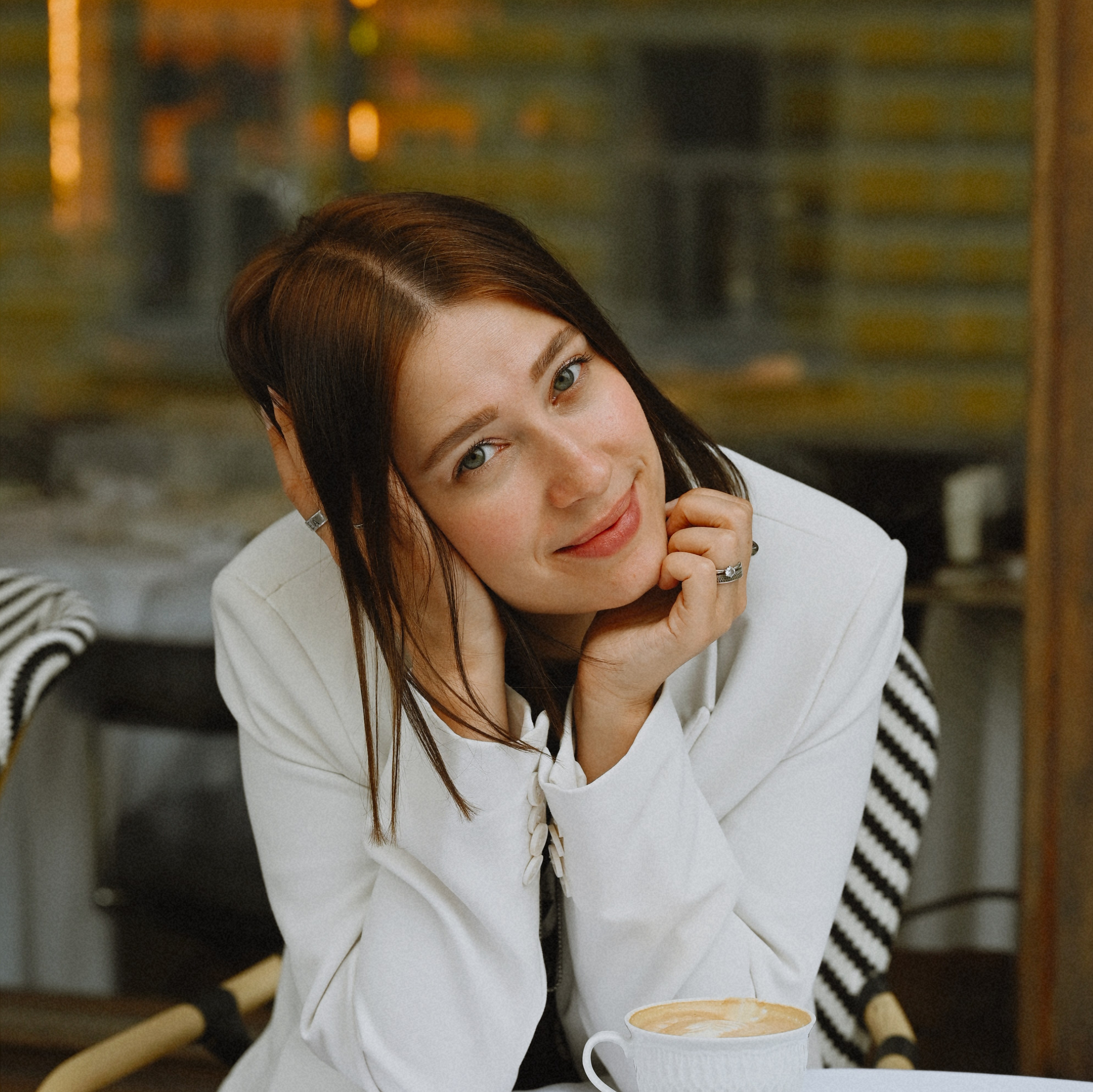 Девушка в белом пиджаке сидит в кафе