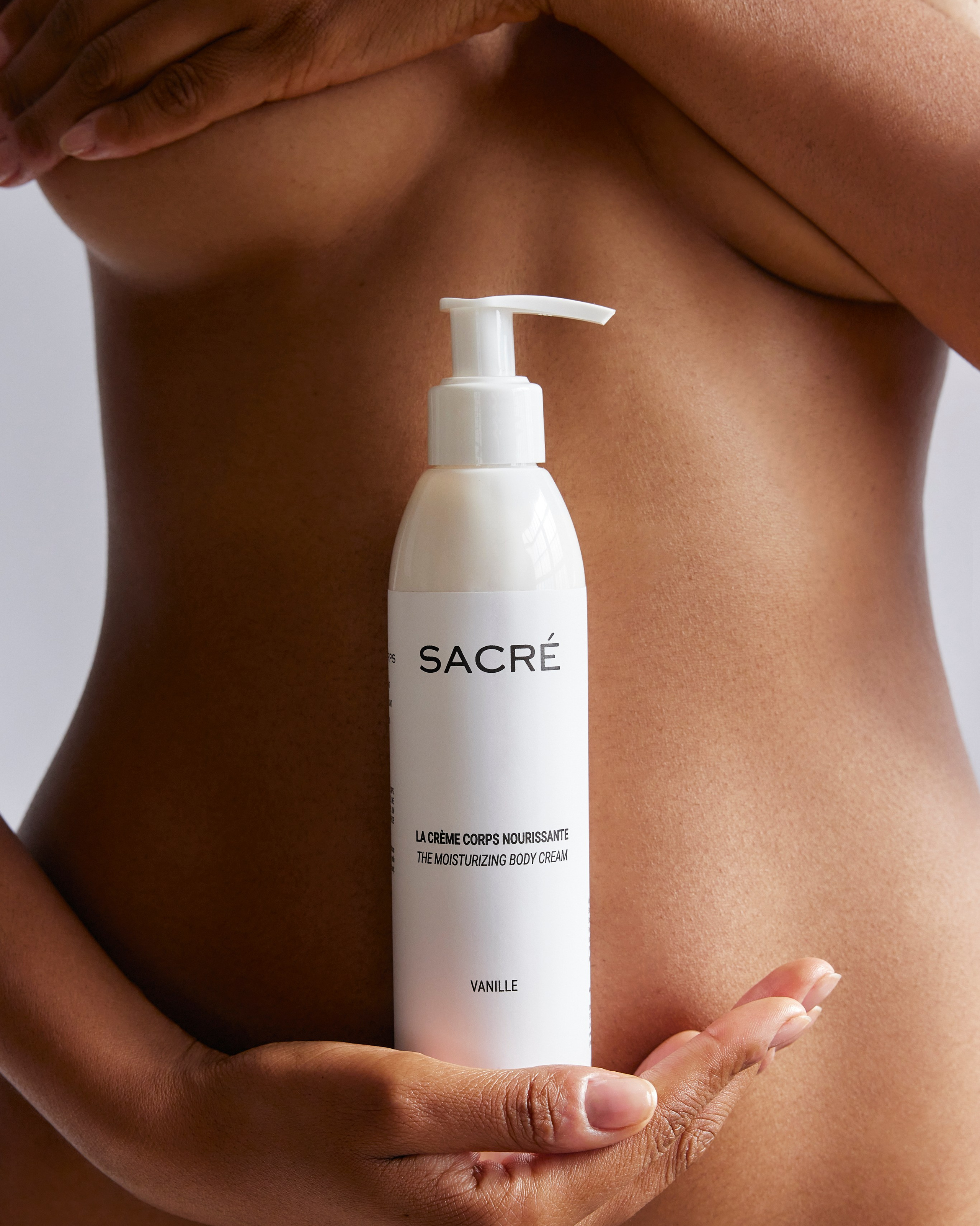 Premium body lotion bottle held against clean, natural skin for a high-end beauty brand campaign.