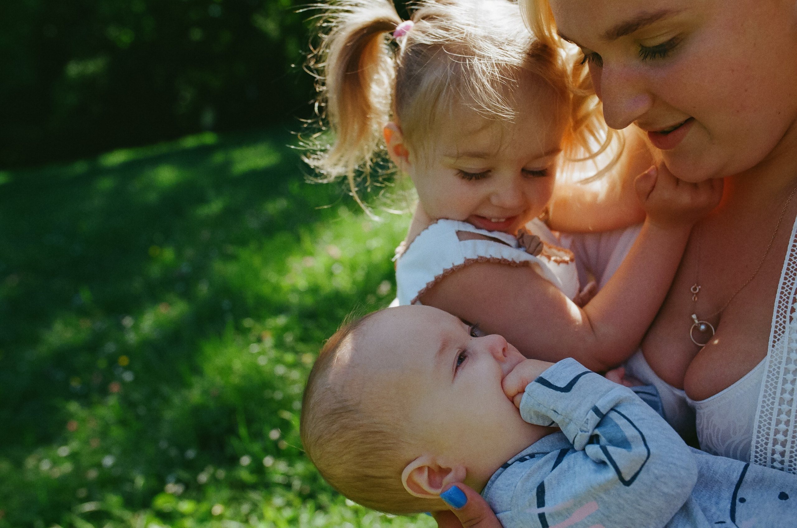 a mother and daughter look at a newborn baby brother