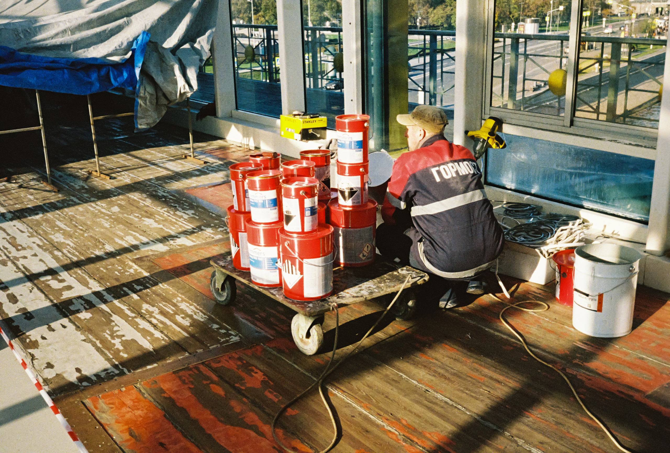 Мужчина в спецовке Гормост красит пол внутри моста Богдана Хмельницкого