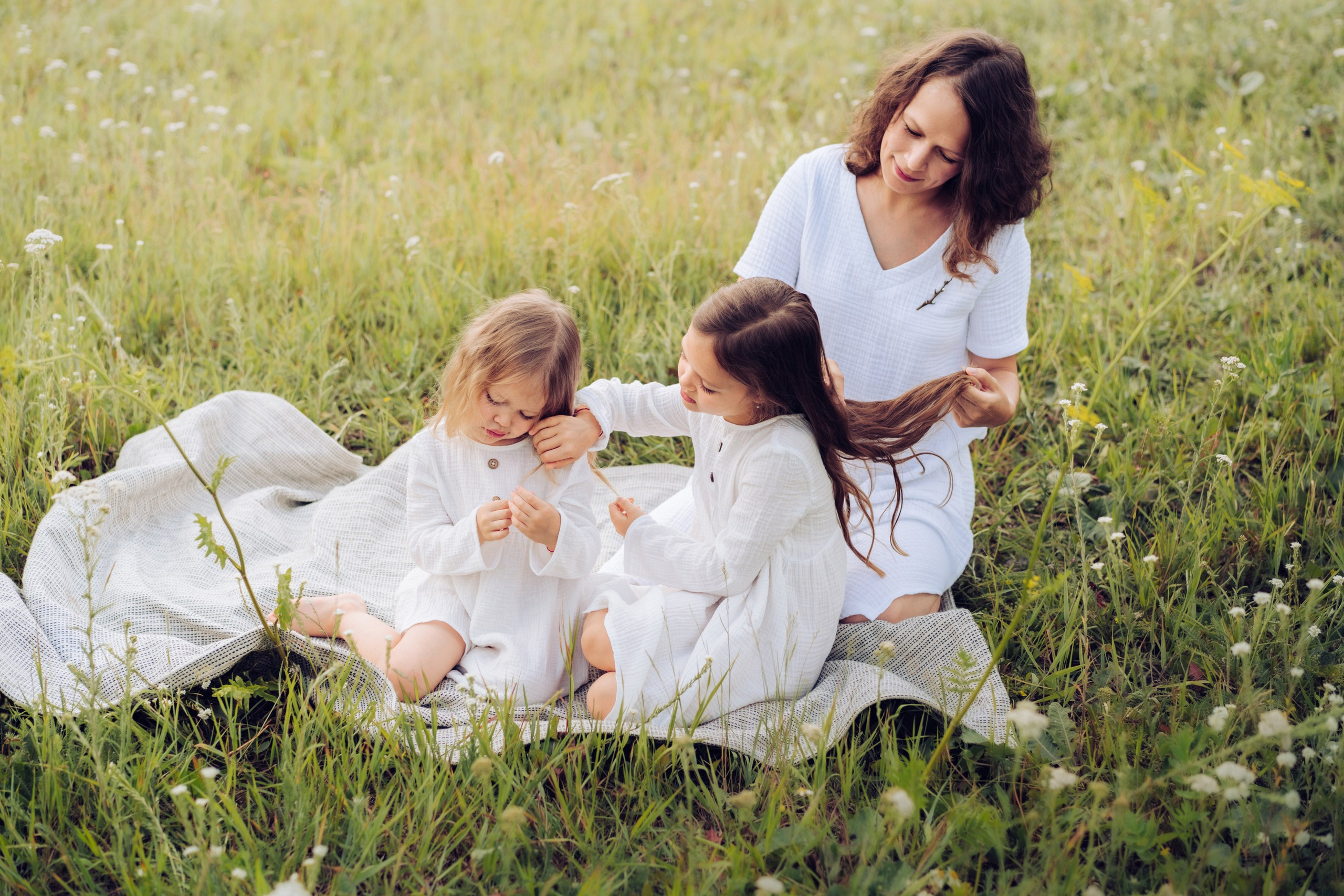 Семейная съемка, мама расчесвает волосы дочери, проявляя заботу