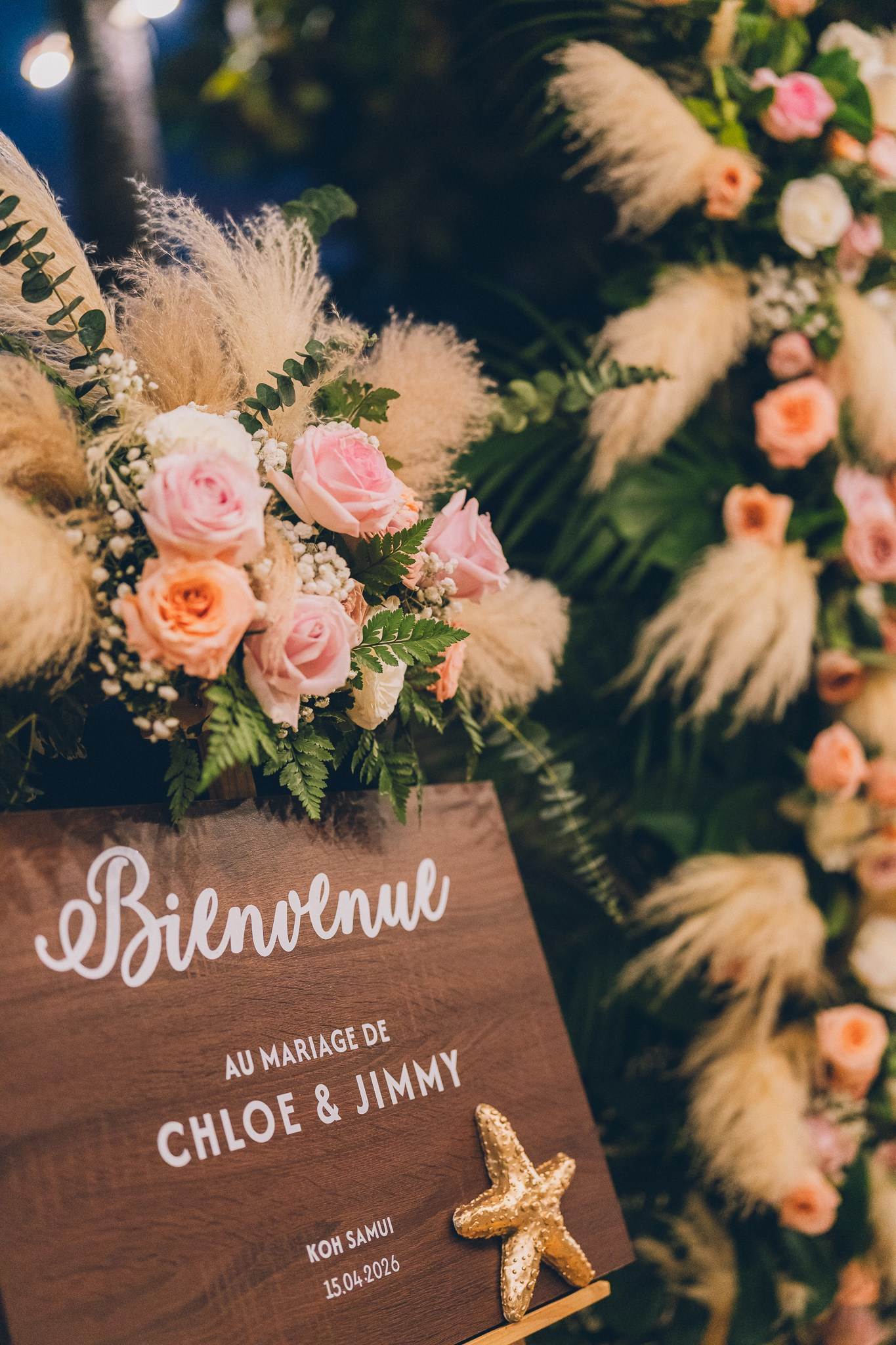 Wedding welcome sign decorated with pink and peach roses, pampas grass and greenery in Koh Samui.
