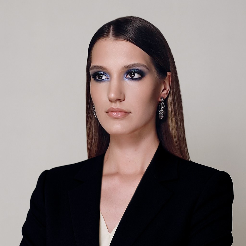 Портрет уверенной женщины в строгом чёрном костюме на светлом фоне.