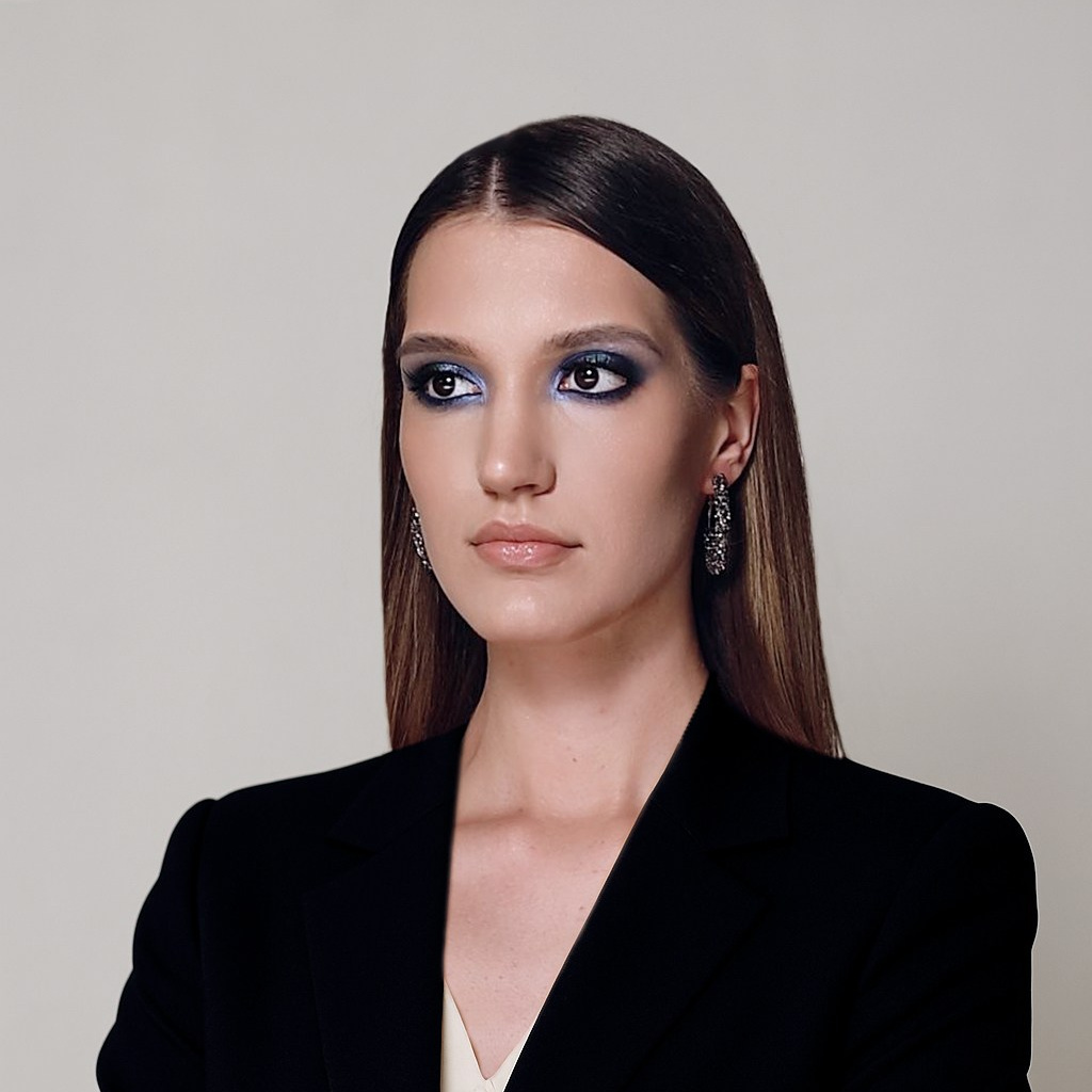 Деловой портрет уверенной женщины в строгом чёрном костюме на светлом фоне.