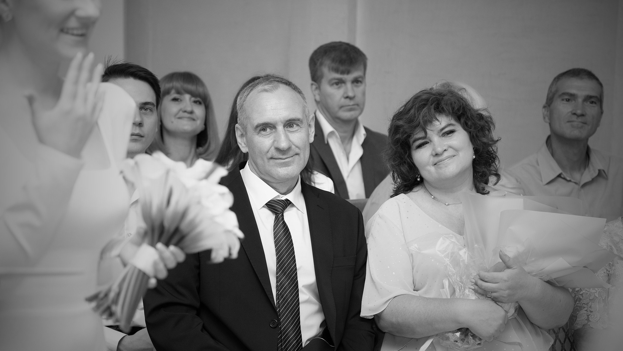 папа жениха влюбленно и с радостью смотрит на вновь обручившихся детей на регистрации брака в загсе