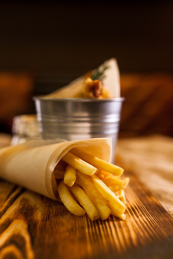 Фотография меню и блюд. Картофель фри жареная картошка в кульке, необычная подача блюда на деревянном подносе.