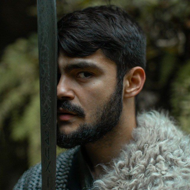 Человек смотрит в камеру, прижав меч к лицу - Дмитрий Дикий