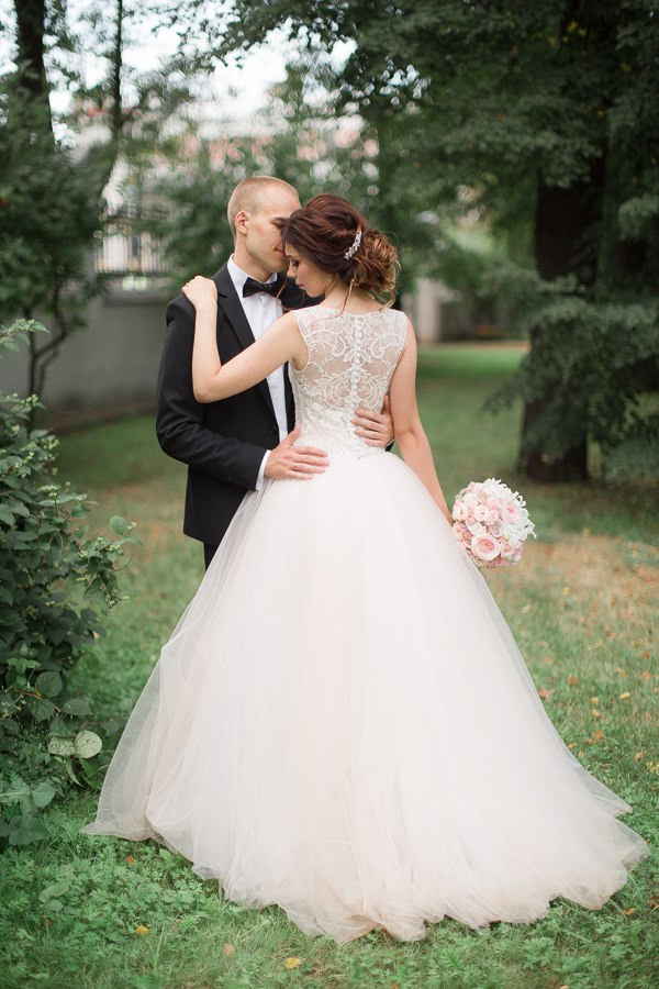 Молодая пара, сидящая на берегу озера, с пучками нежно розовых и белых цветов вокруг