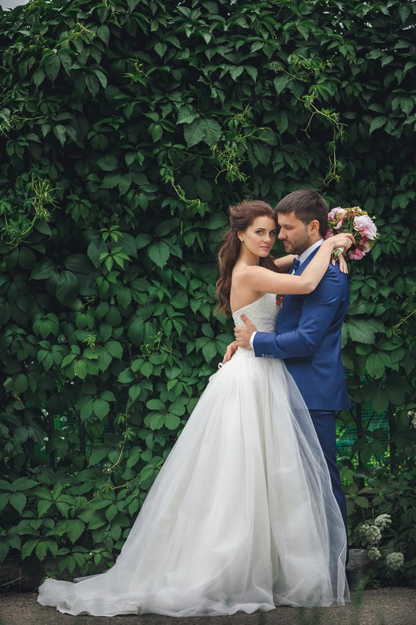 Невеста держит в руках букет из роз, раскрывая его перед женихом, создавая эффект сюрприза и радости