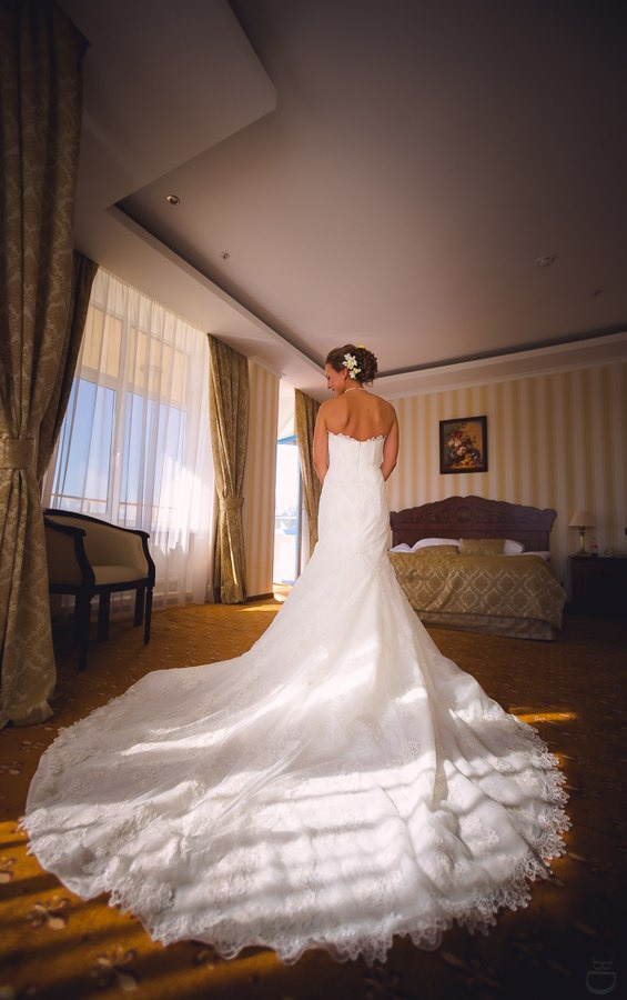 Невеста и жених, стоящие у самого берега озера, где водные лилии создают нежные отражения