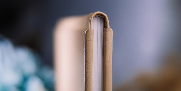 Бежевая кожаная обложка фотокниги с акцентом на премиальный скругленный корешок. Ручная работа, подчеркивающая статус изделия.