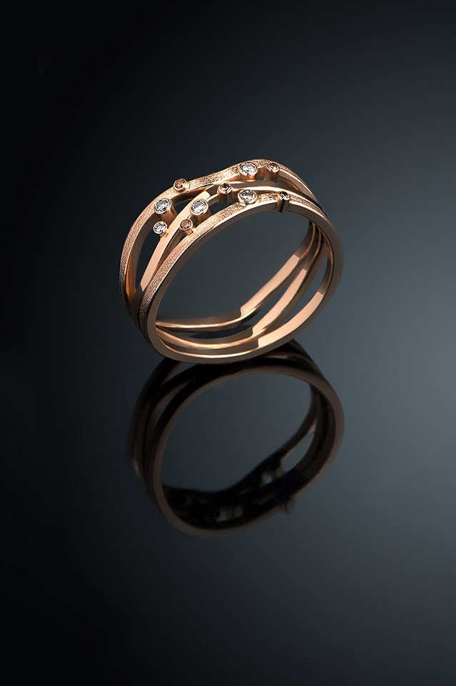 Золотое кольцо с камнями на чёрном фоне.