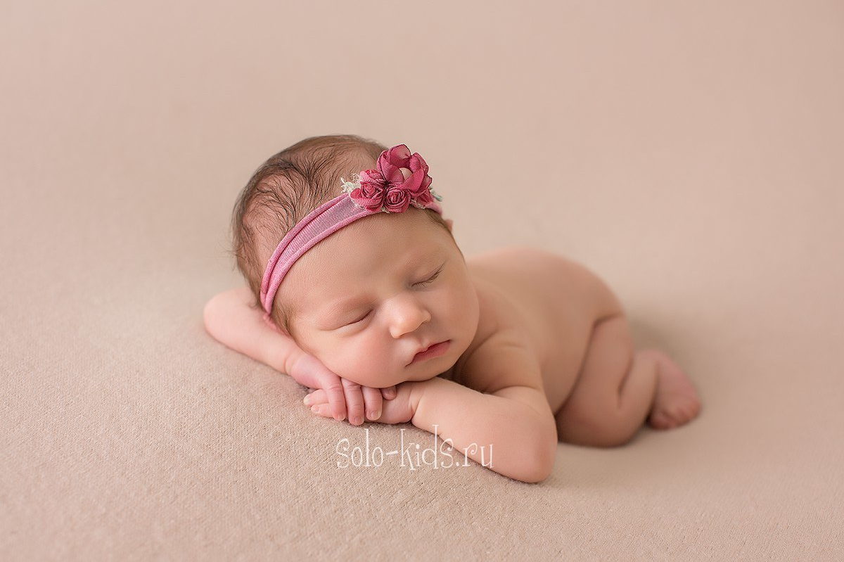 Новорожденная малышка лежит на животике