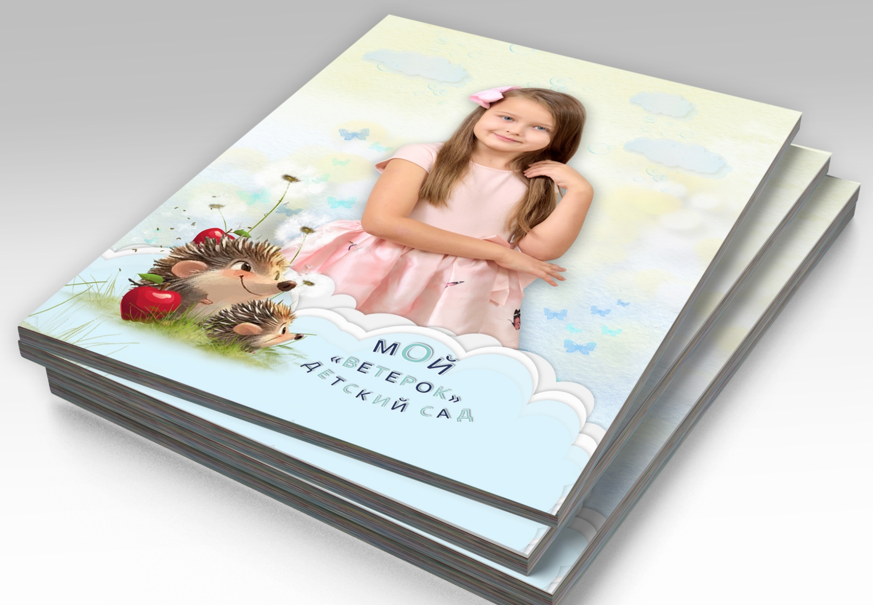 Стопка альбомов выпускника детского сада, на титульной стороне портрет выпускницы.