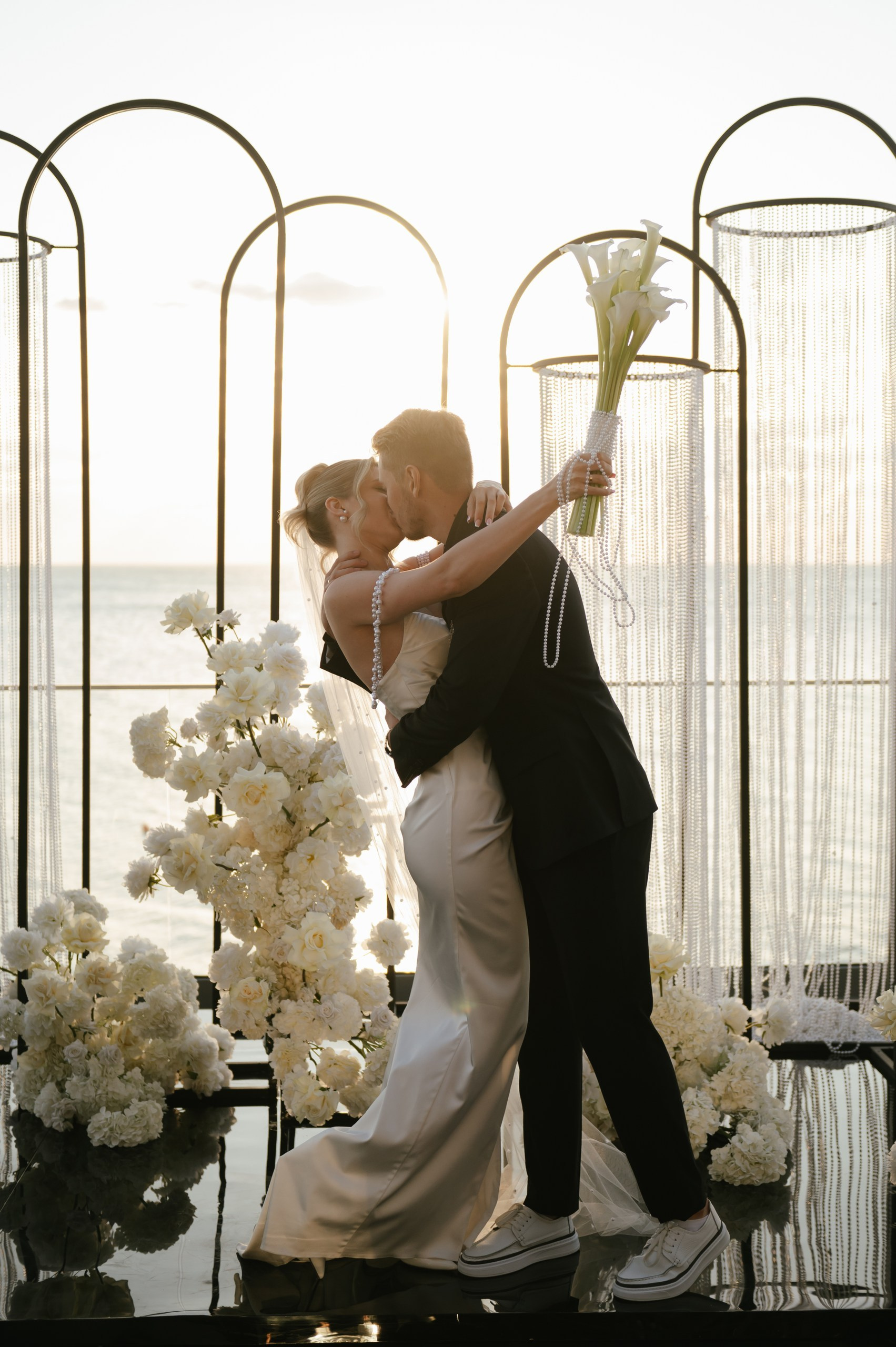 Жених и невеста целуются у алтаря на берегу моря в Крыму  