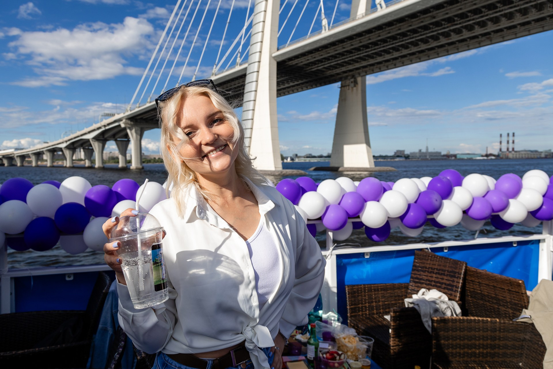 Фото красивой девушки с коктейлем в руке на теплоходе на фоне Вантового моста в Питере