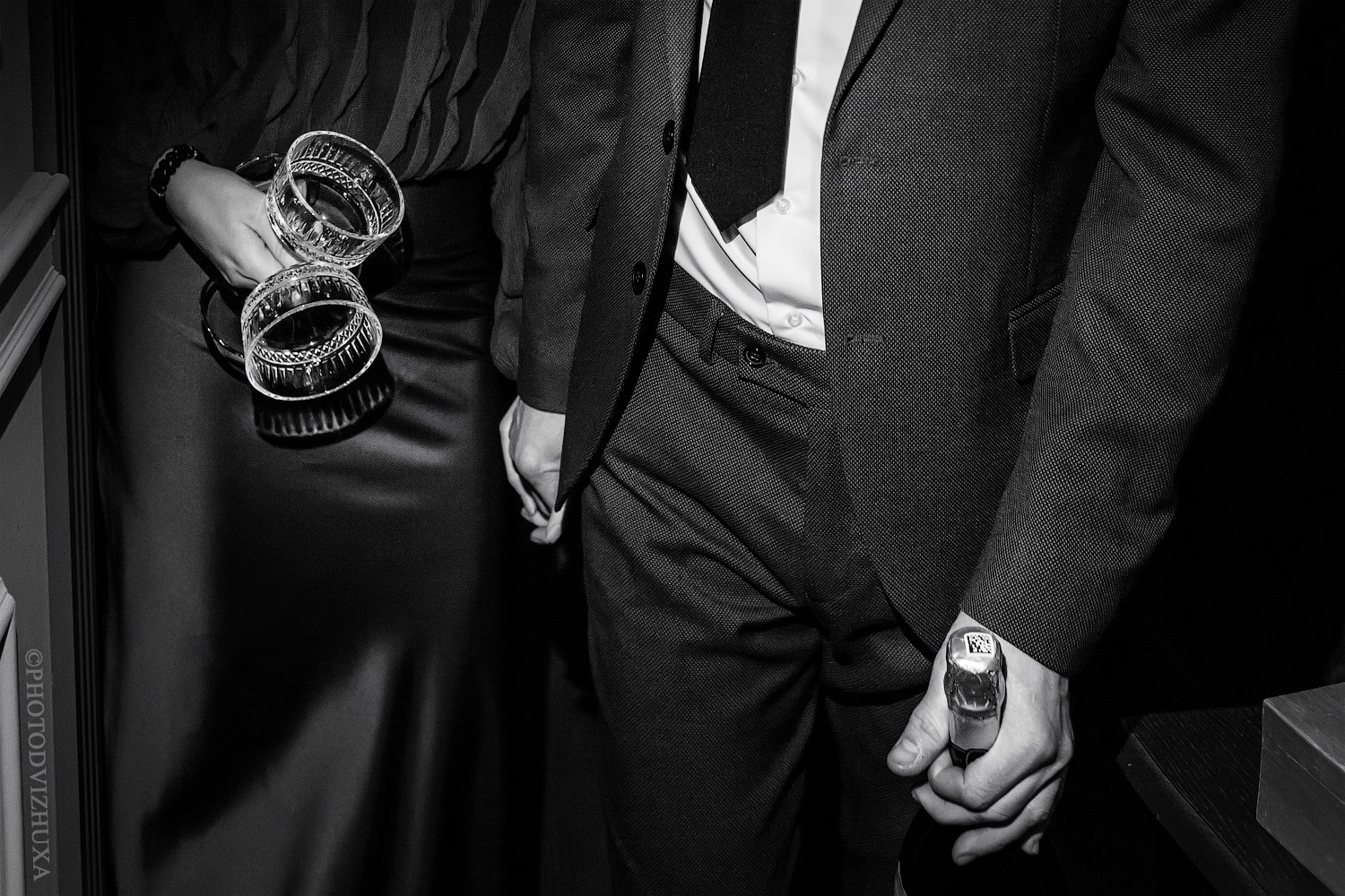 Мужчина и женщина идут в номер, держат в руках бутылку шампанского и бокалы, чб