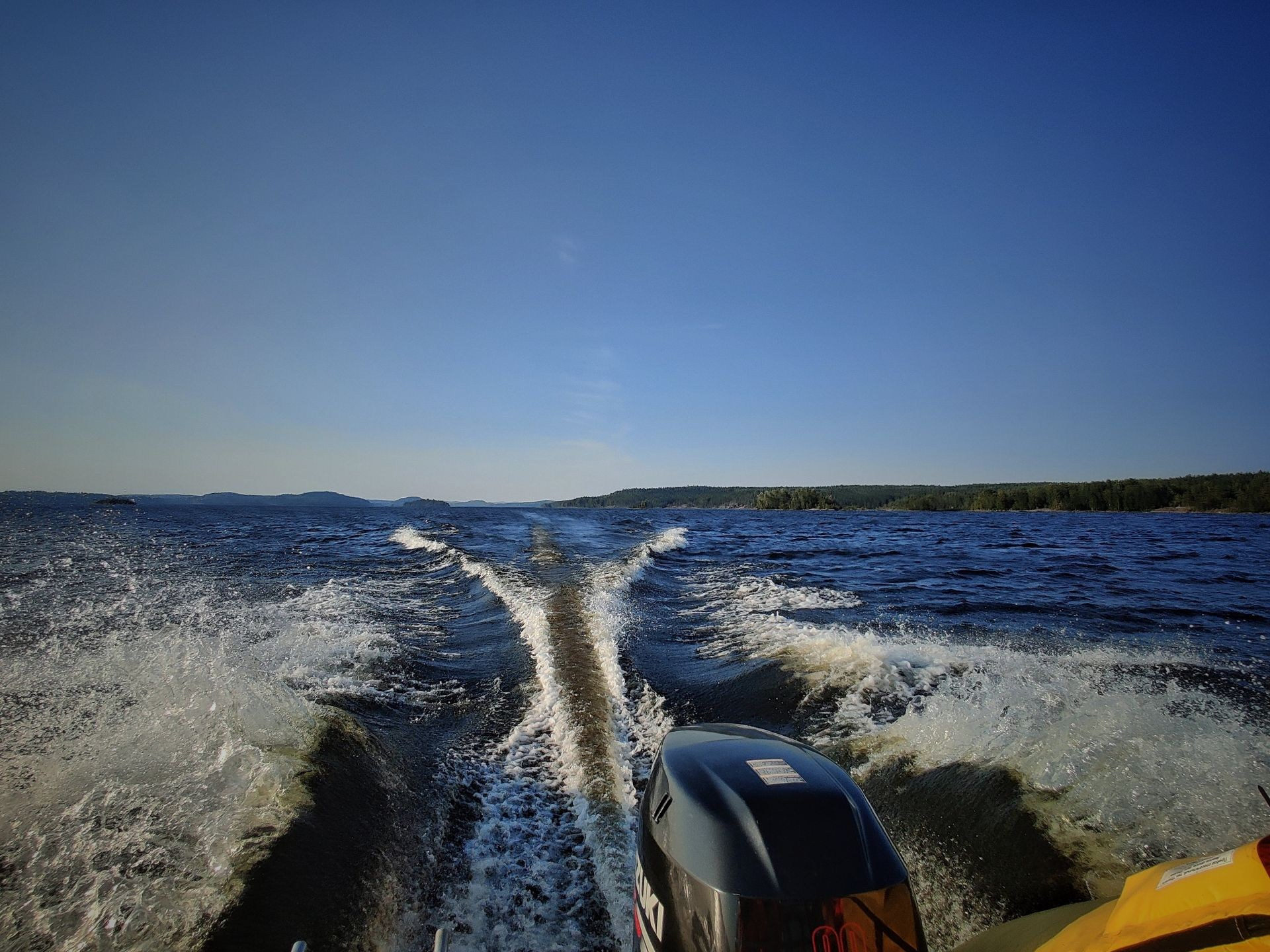 Лодочный мотор на фоне спокойного озера с ясным небом