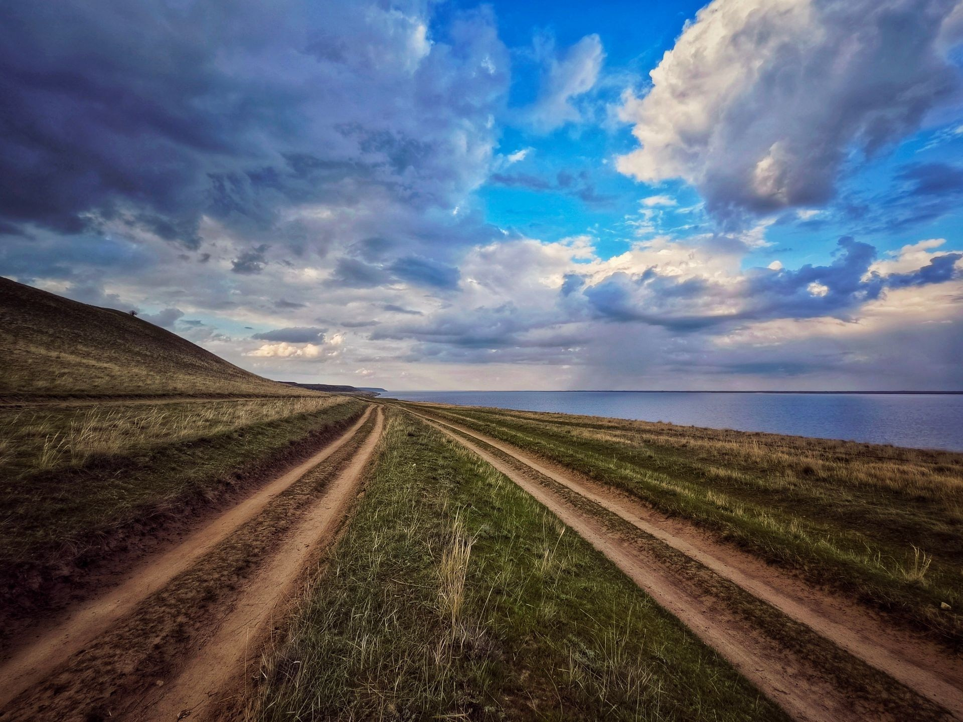 Просёлочная дорога в степи под облачным небом