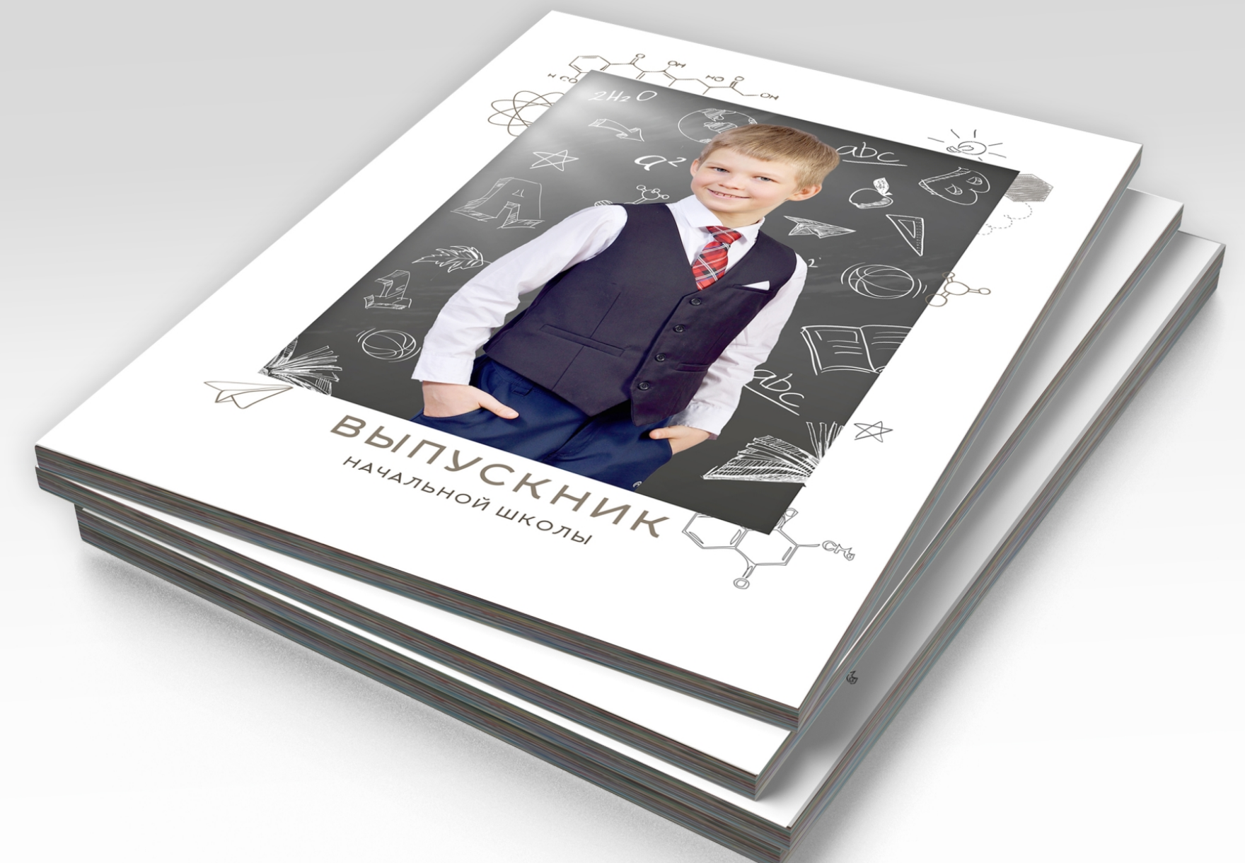 Стопка альбомов выпускника начальной школы, на титульной стороне портрет выпускника.
