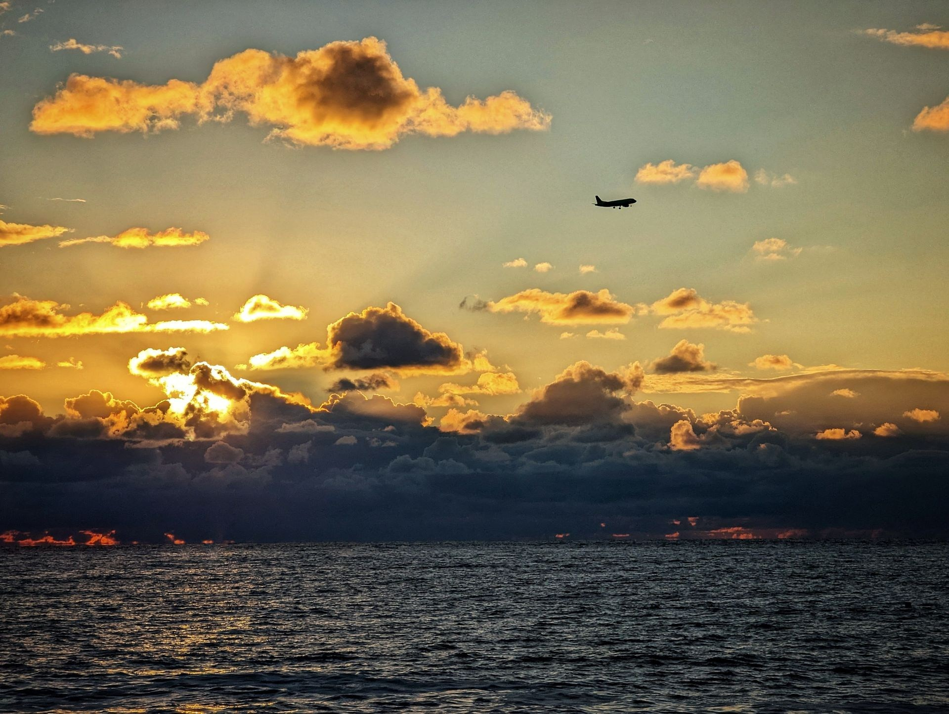 Самолет летит над Черным морем на фоне заката и облаков