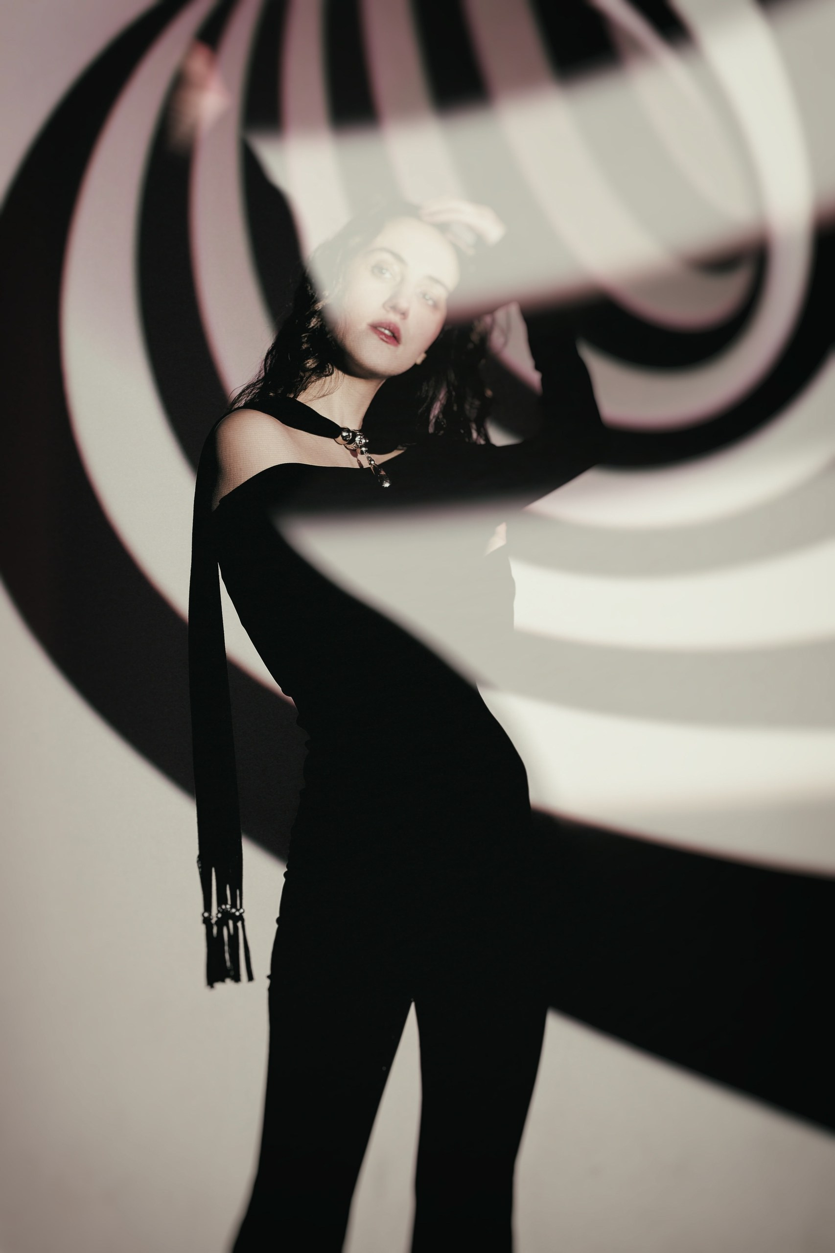 Арт-портрет девушки в черном на фоне спиральной гипнотической проекции, оп-арт эффект, концептуальная фотография