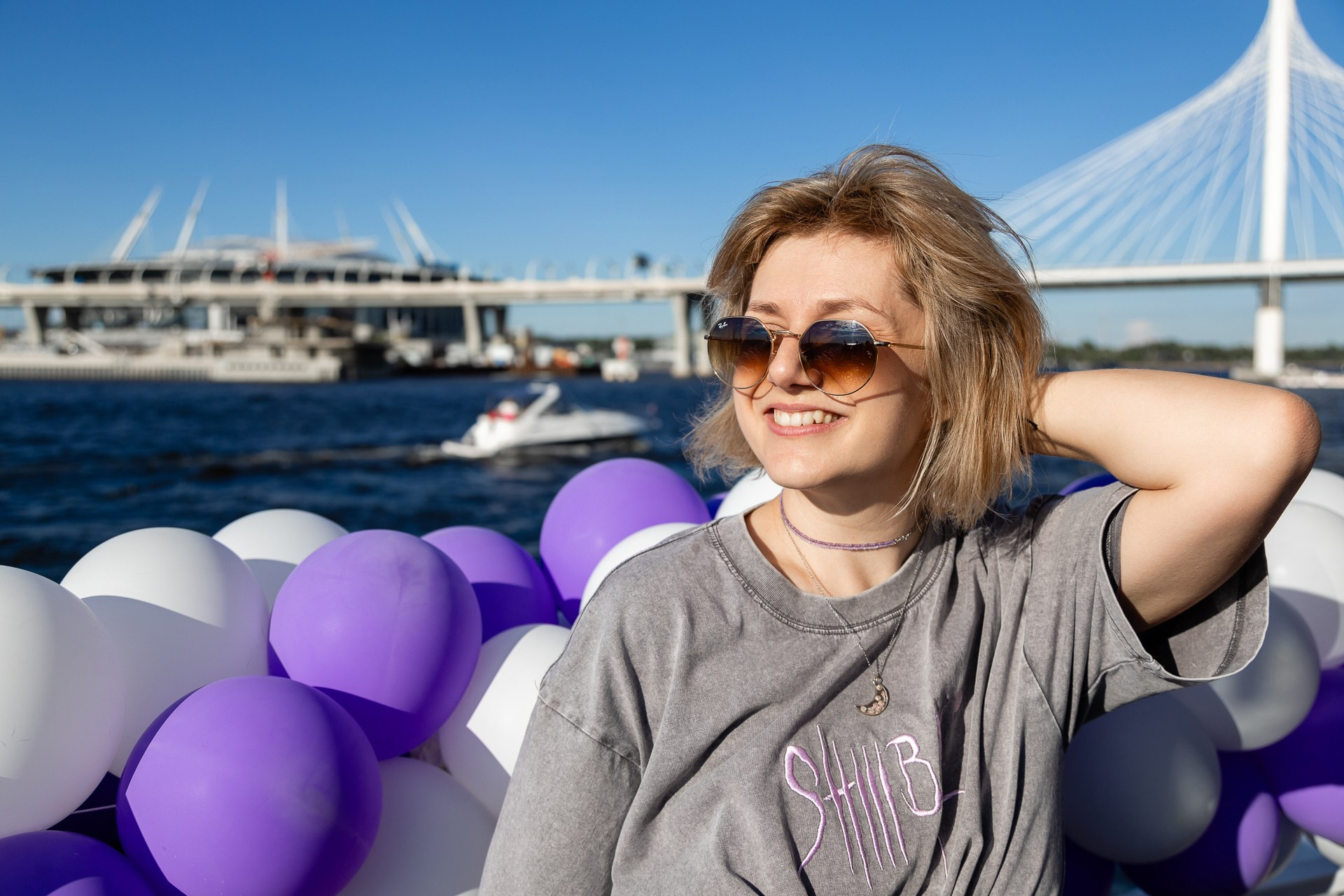 Фото красивой девушки на теплоходе, украшенном шариками, на фоне Вантового моста в Санкт-Петербурге