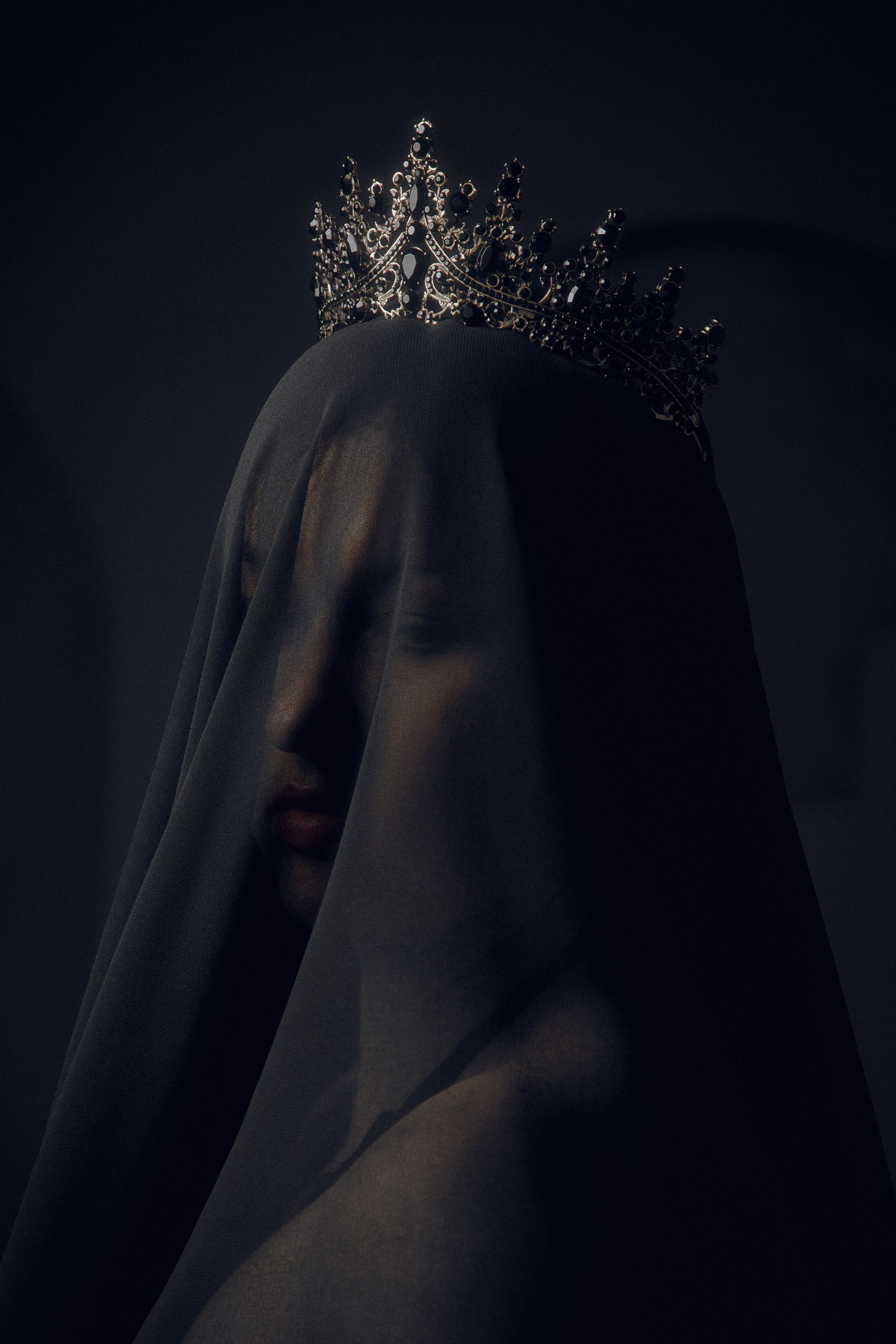 Студийный портрет девушки в короне с использованием черной ткани.