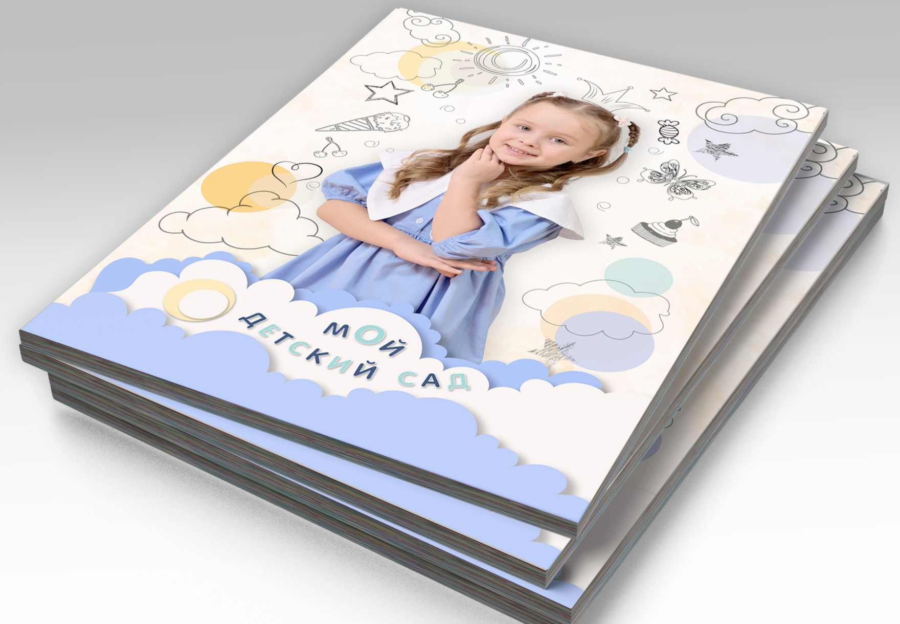 Стопка альбомов выпускника детского сада, на титульной стороне портрет выпускницы.