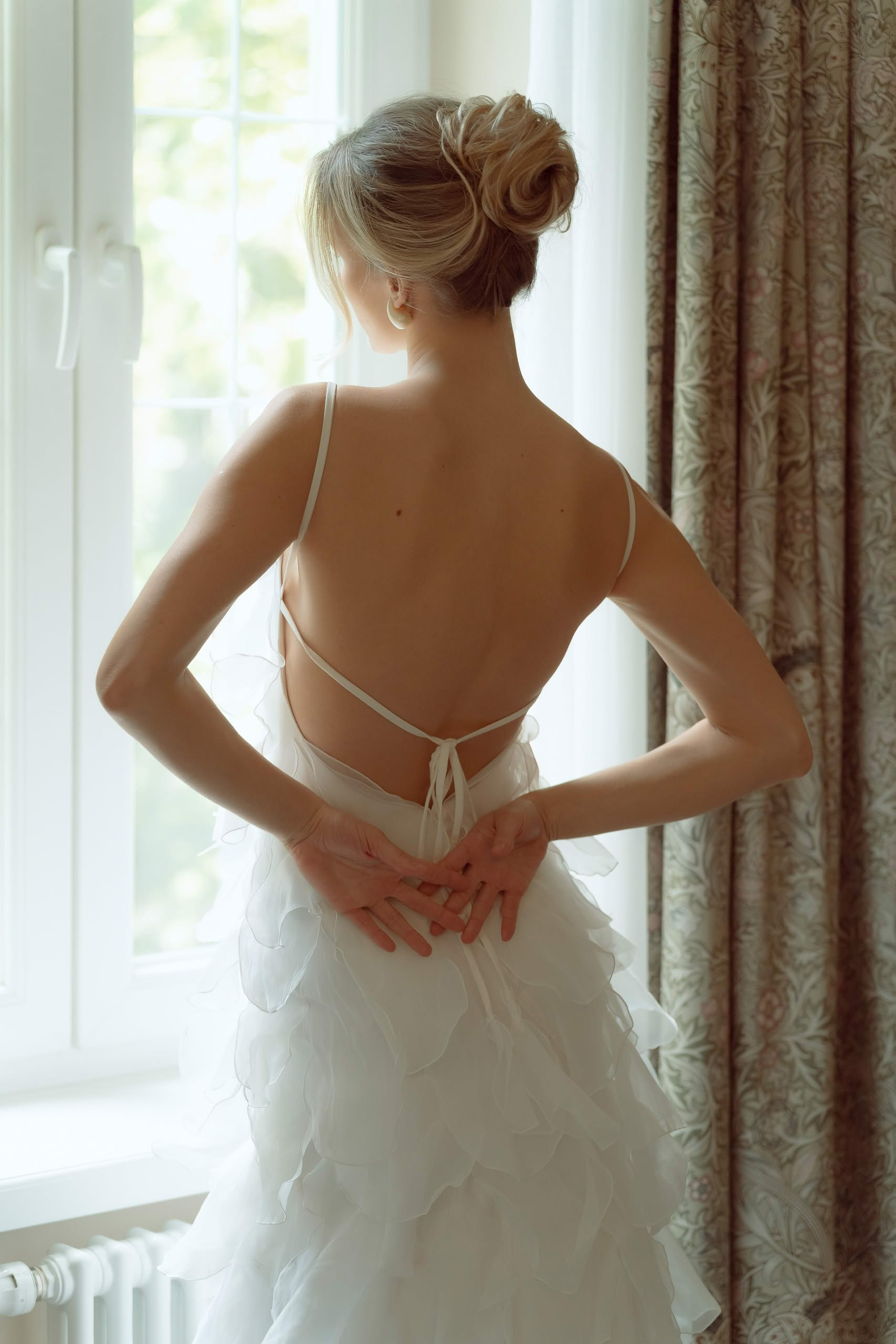 утро невесты невеста со спины у окна платье сборы невесты естественный свет