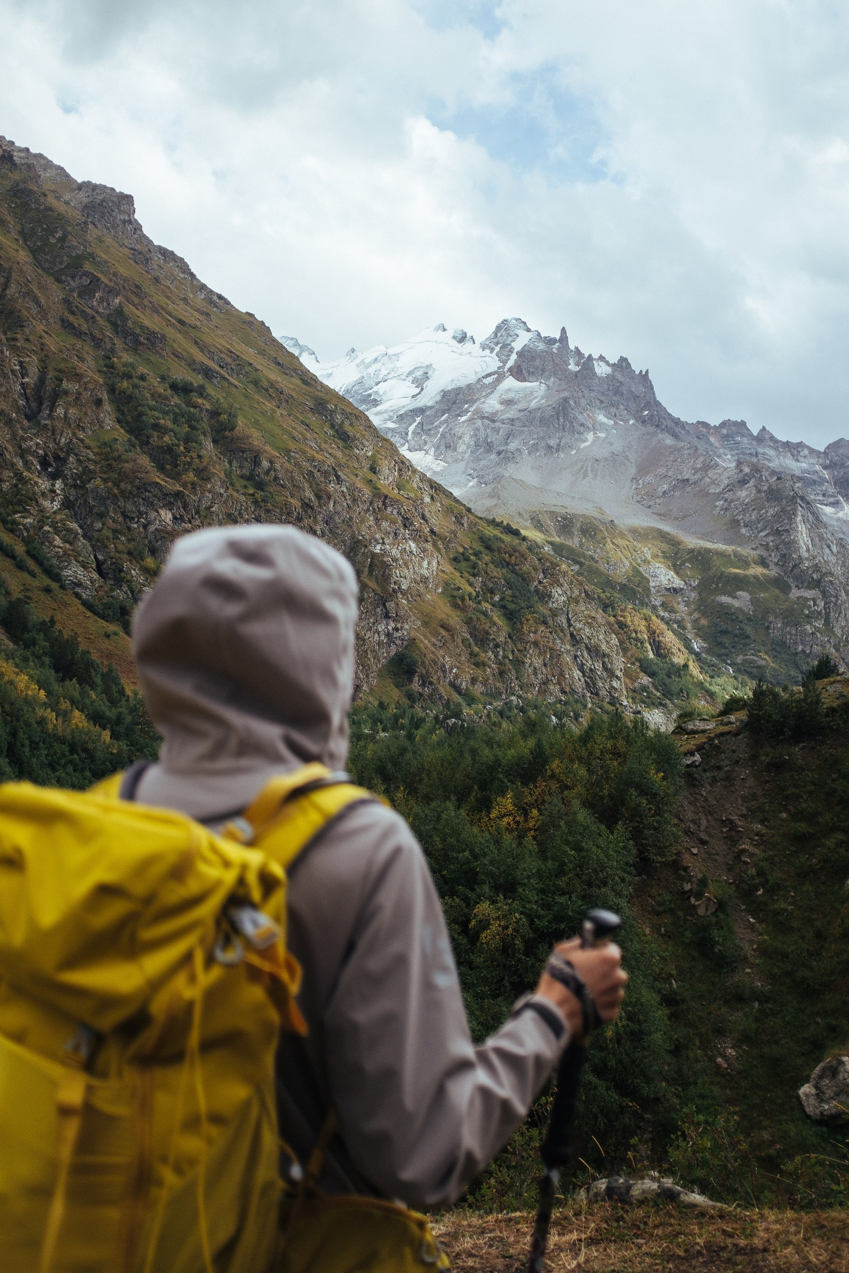 Турист с рюкзаком на трекинге в Приэльбрусье, горная долина и вершины