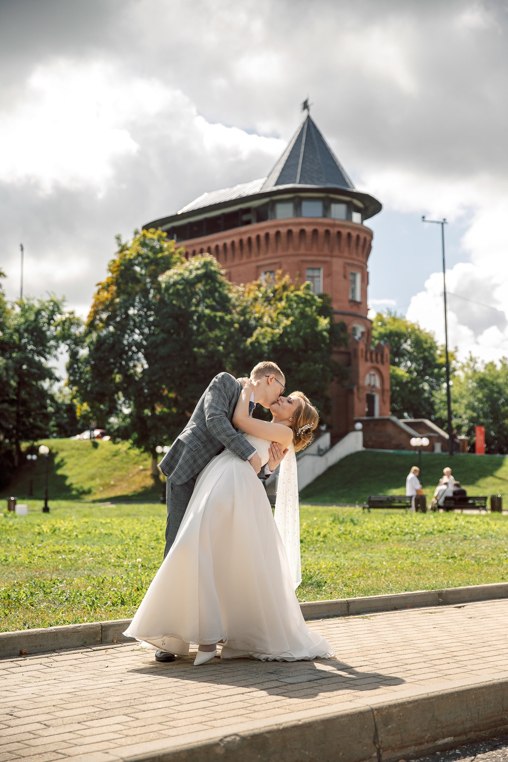 Поцелуй жениха и невесты на фоне башни