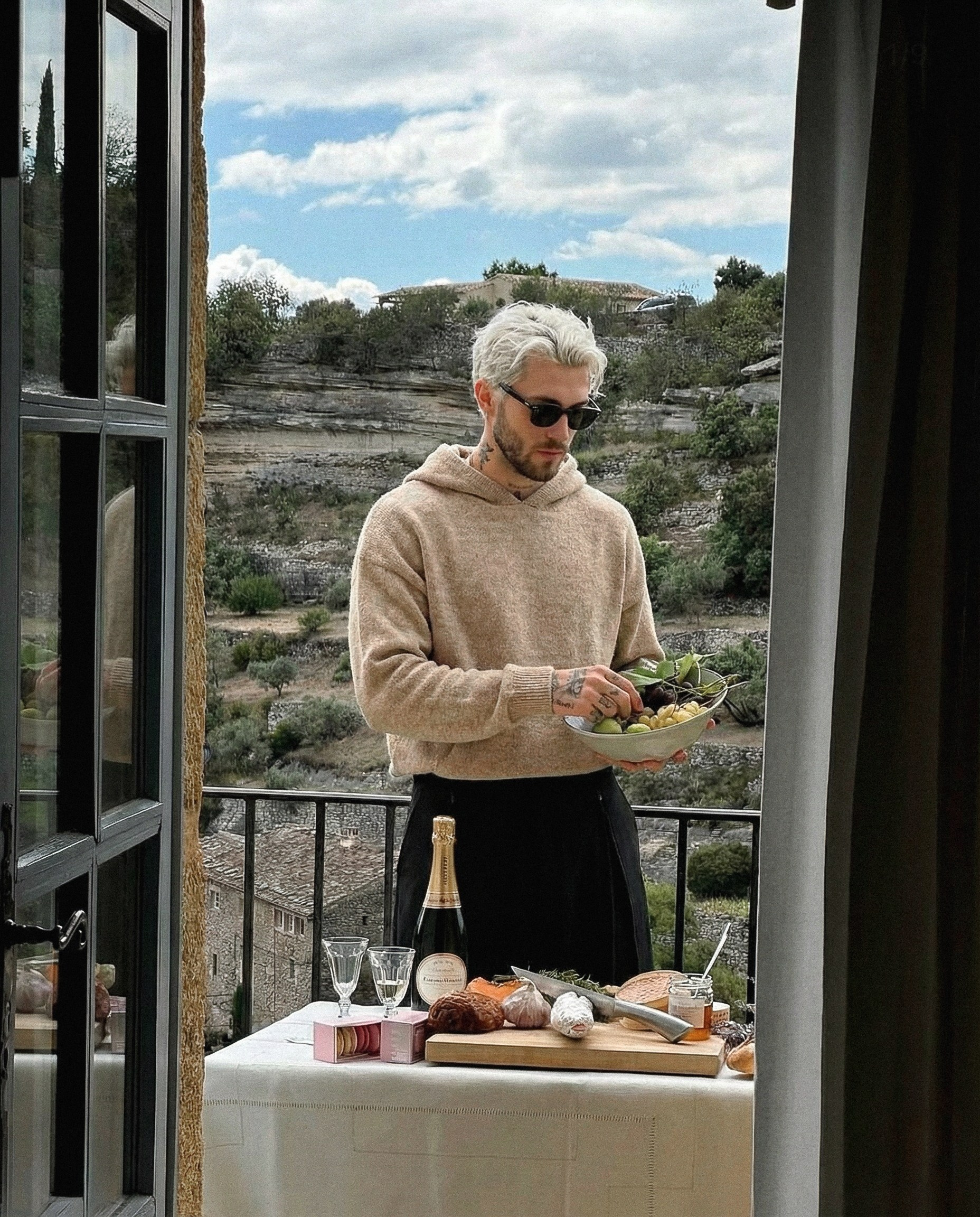ИИ-генерация lifestyle-сцены для бренда одежды — мужчина в светлом свитере сервирует стол на террасе с видом на природу