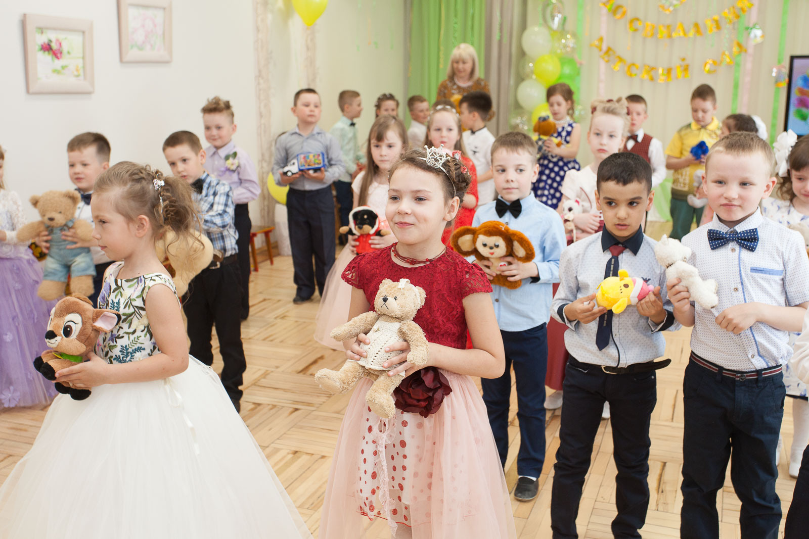 Выпускники детского сада танцуют  с мягкими игрушками на выпускном утреннике в детском саду.