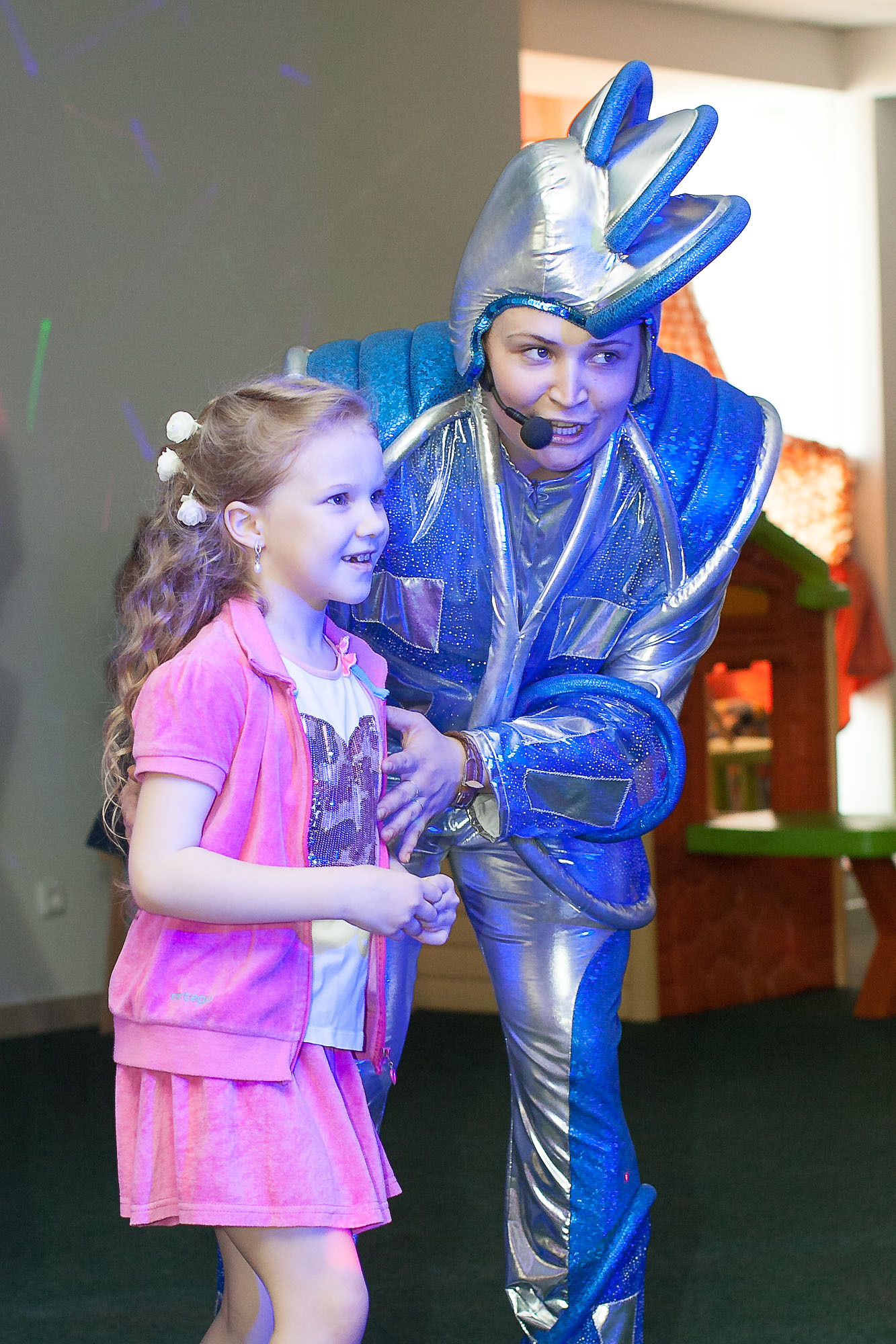 Девочка в розовом платье с аниматором в космическом костюме.