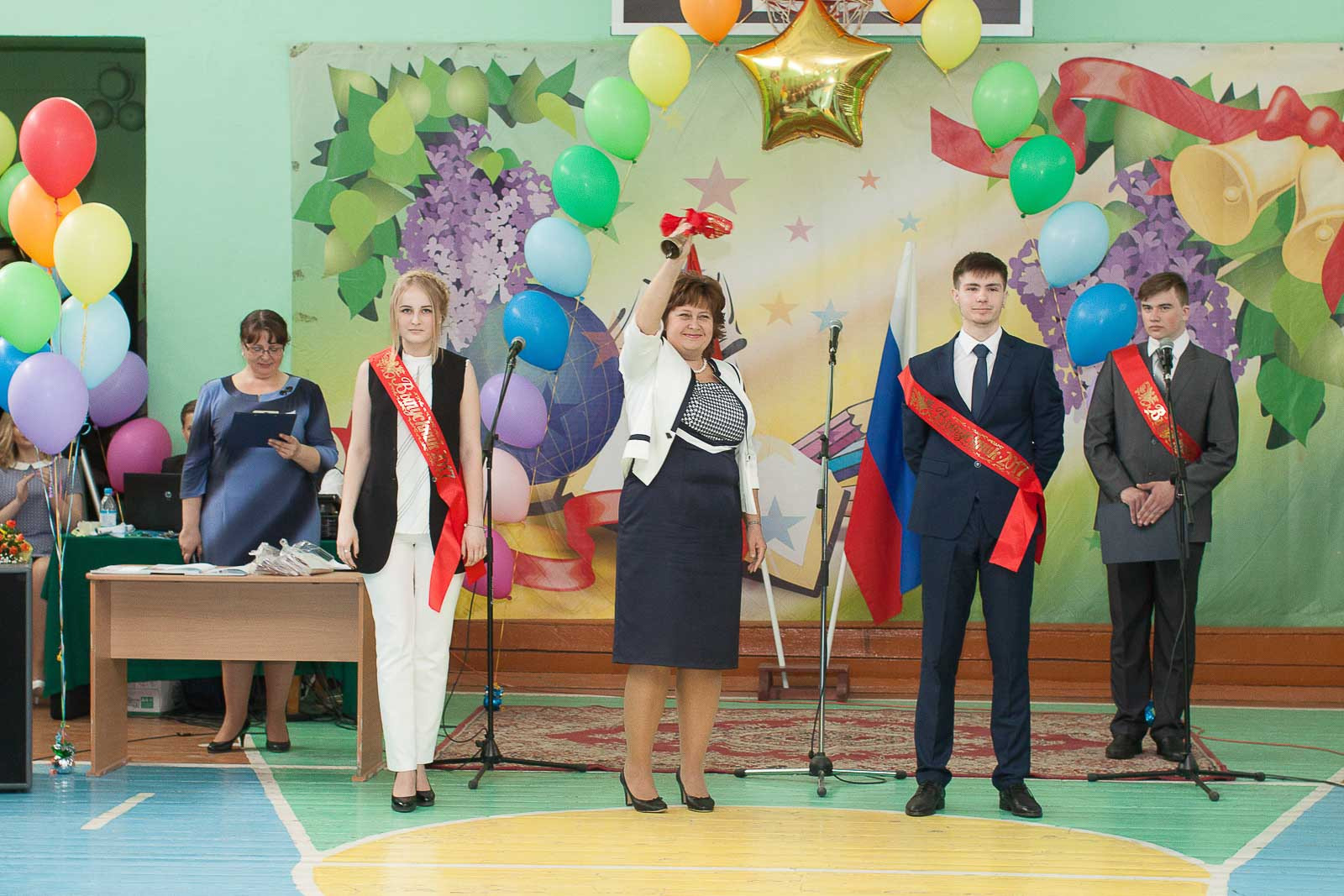 Четыре выпускника и преподаватель в белом пиджаке подают последний звонок 