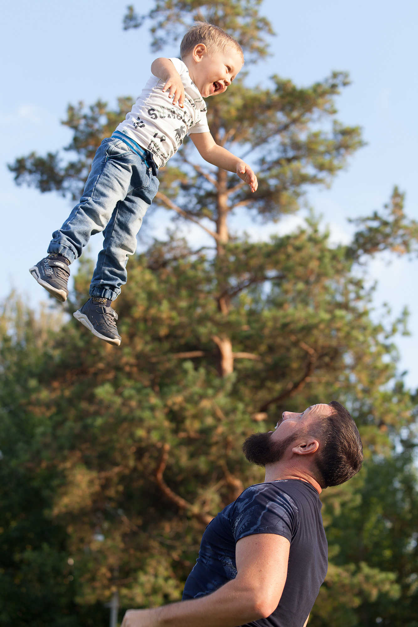 Мальчик завис в воздухе. Его подбросил папа высоко.