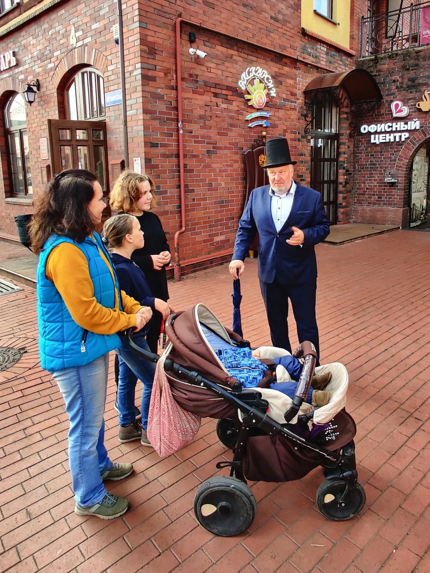 Группа людей с детской коляской на уличной экскурсии в Калининграде