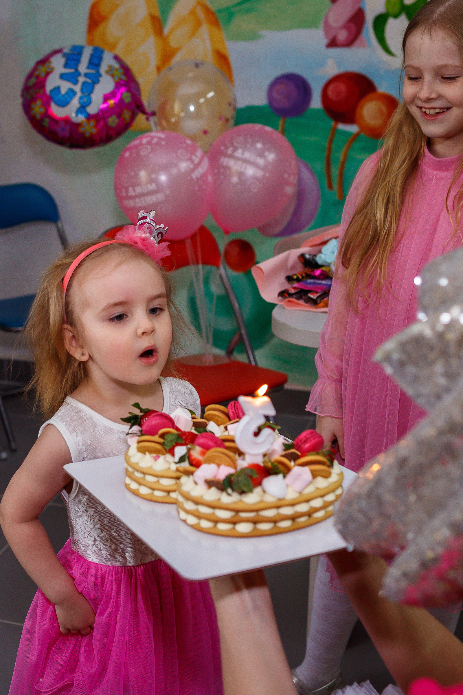 Девочка задувает свечи на праздничном торте