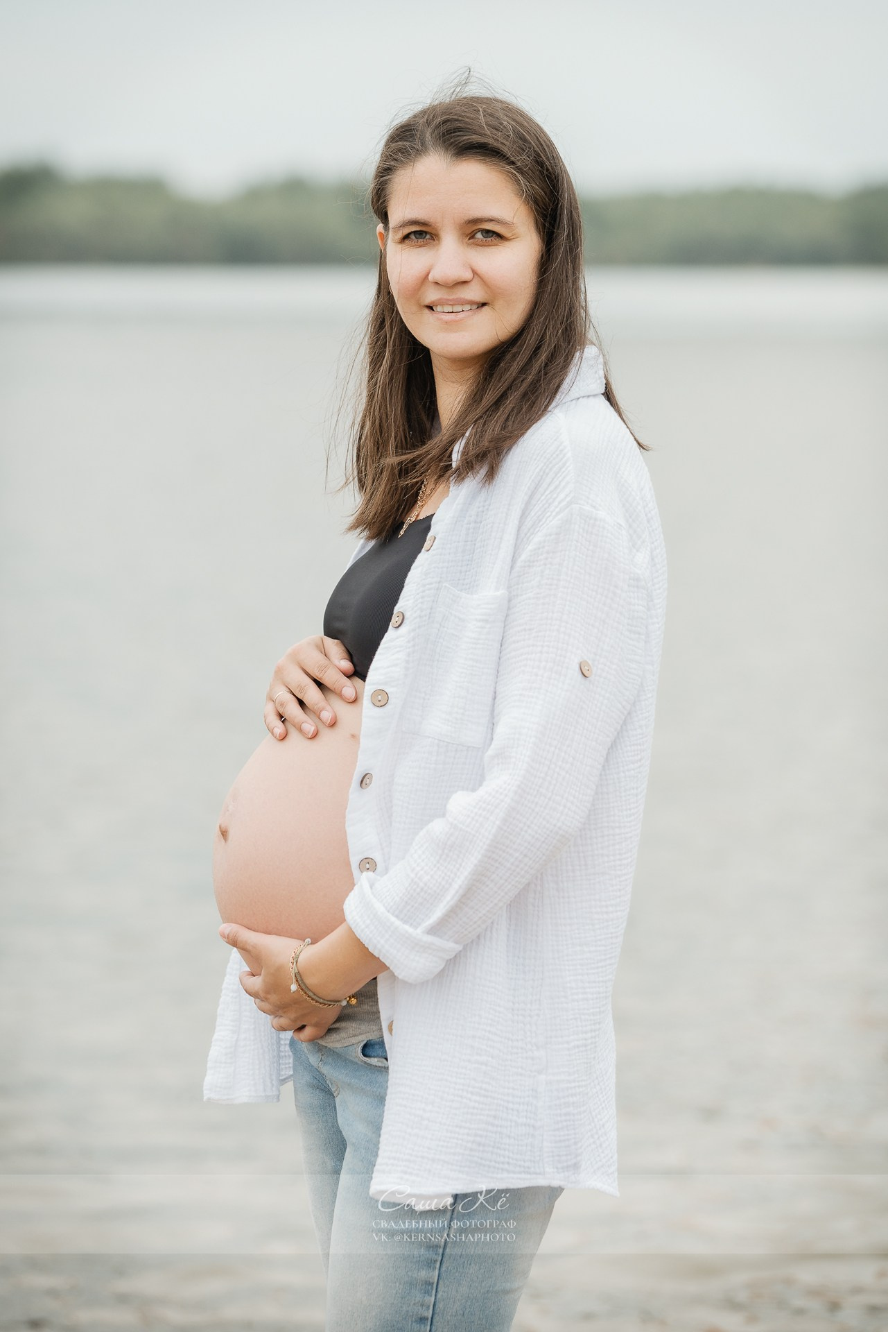 Семейная фотосессия на берегу реки в Новосибирске с фотографом Сашей Кё, беременная девушка улыбается.