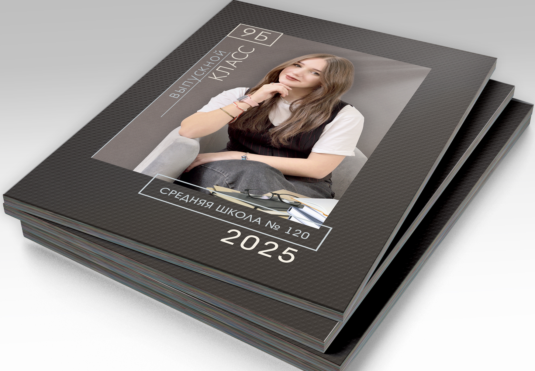 Стопка альбомов выпускника средней школы, на титульной стороне портрет выпускницы.