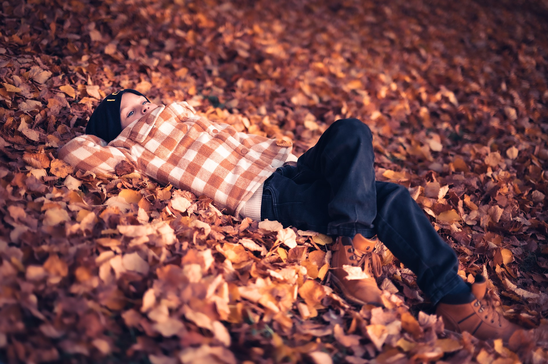 Фотосессия с детьми осенью во Владимире. Ребенок отдыхает на листьях.